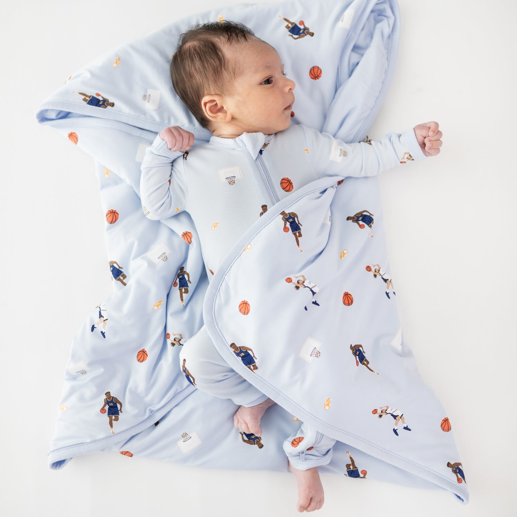 Infant laying on a Baby Blanket in Basketball wearing a matching zippered romper
