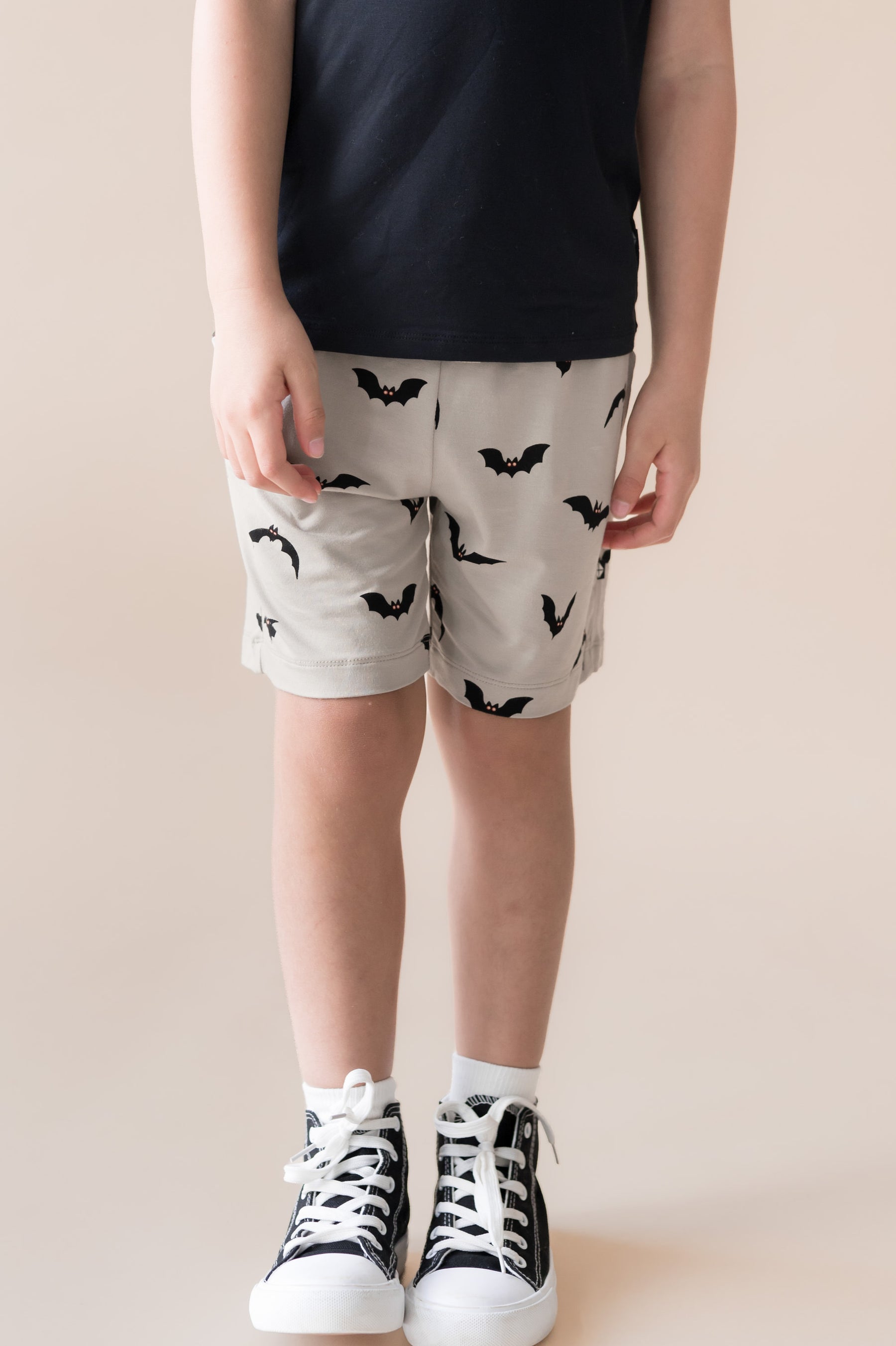Toddler wearing Drawstring Short in Bats print under black T-shirt and shoes on a beige background