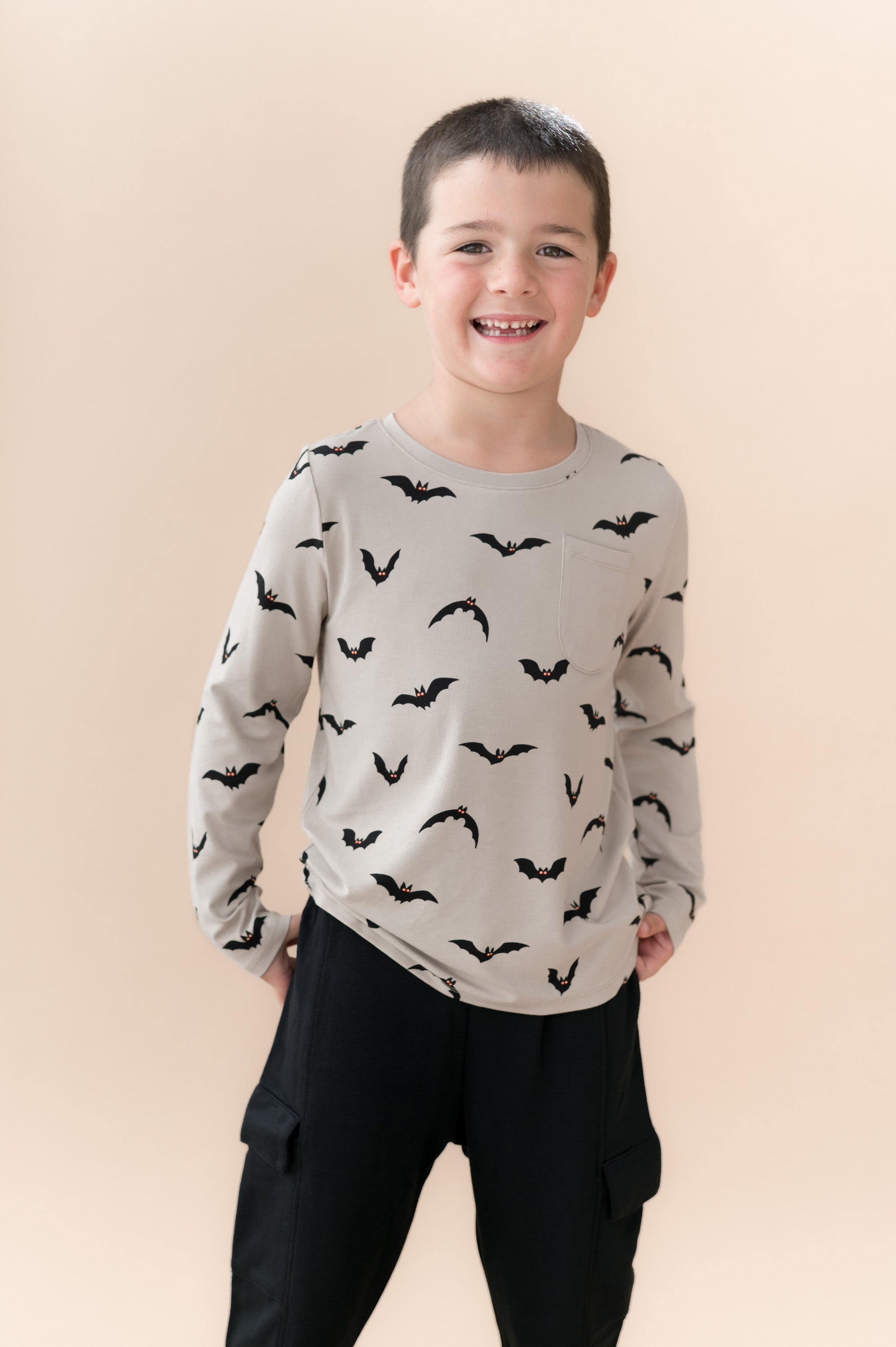 Boy wearing Long Sleeve Toddler Crew Neck Tee in Bats print over black pants on a beige background