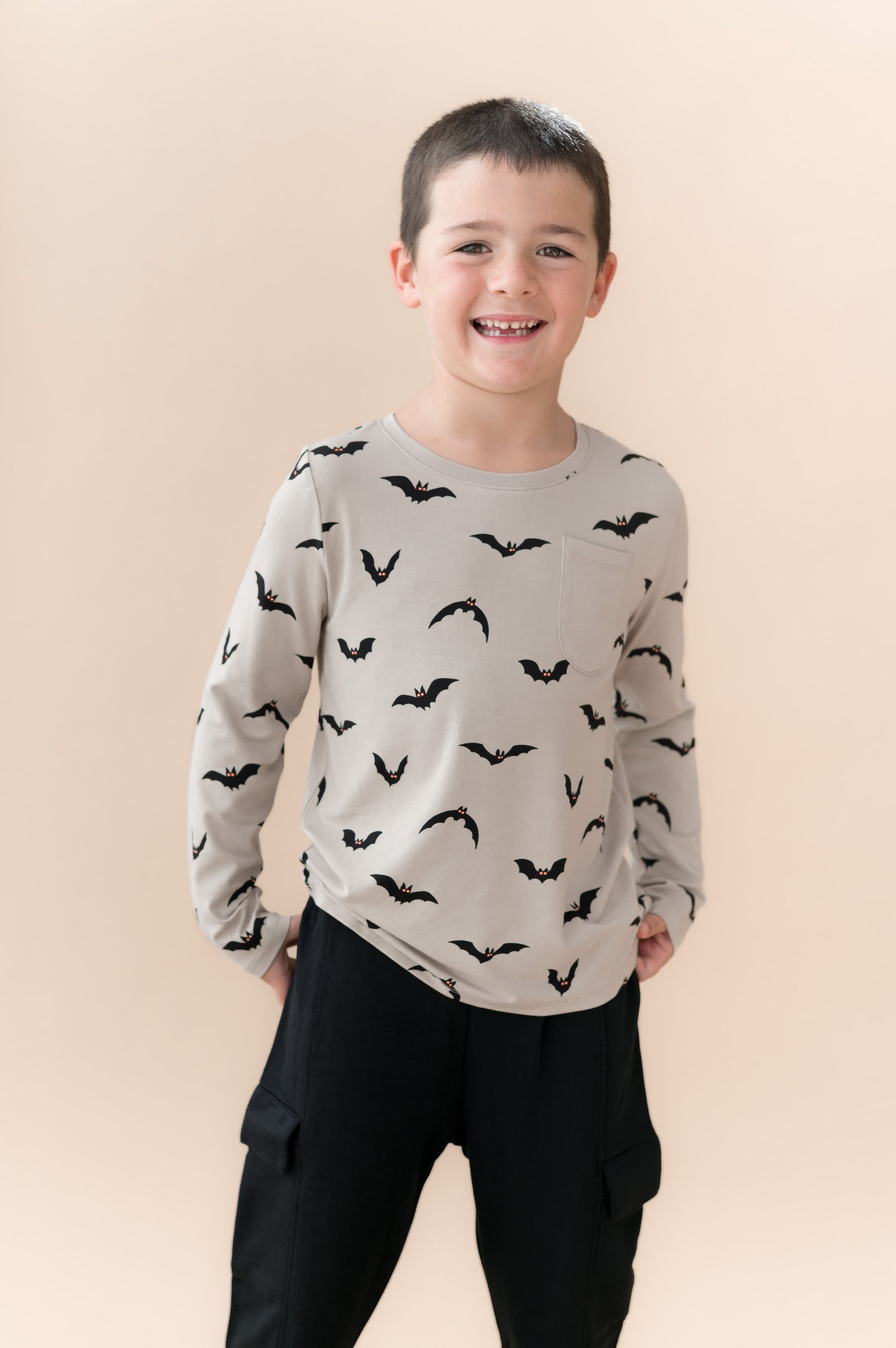 Boy wearing Long Sleeve Toddler Crew Neck Tee in Bats print over black pants on a beige background