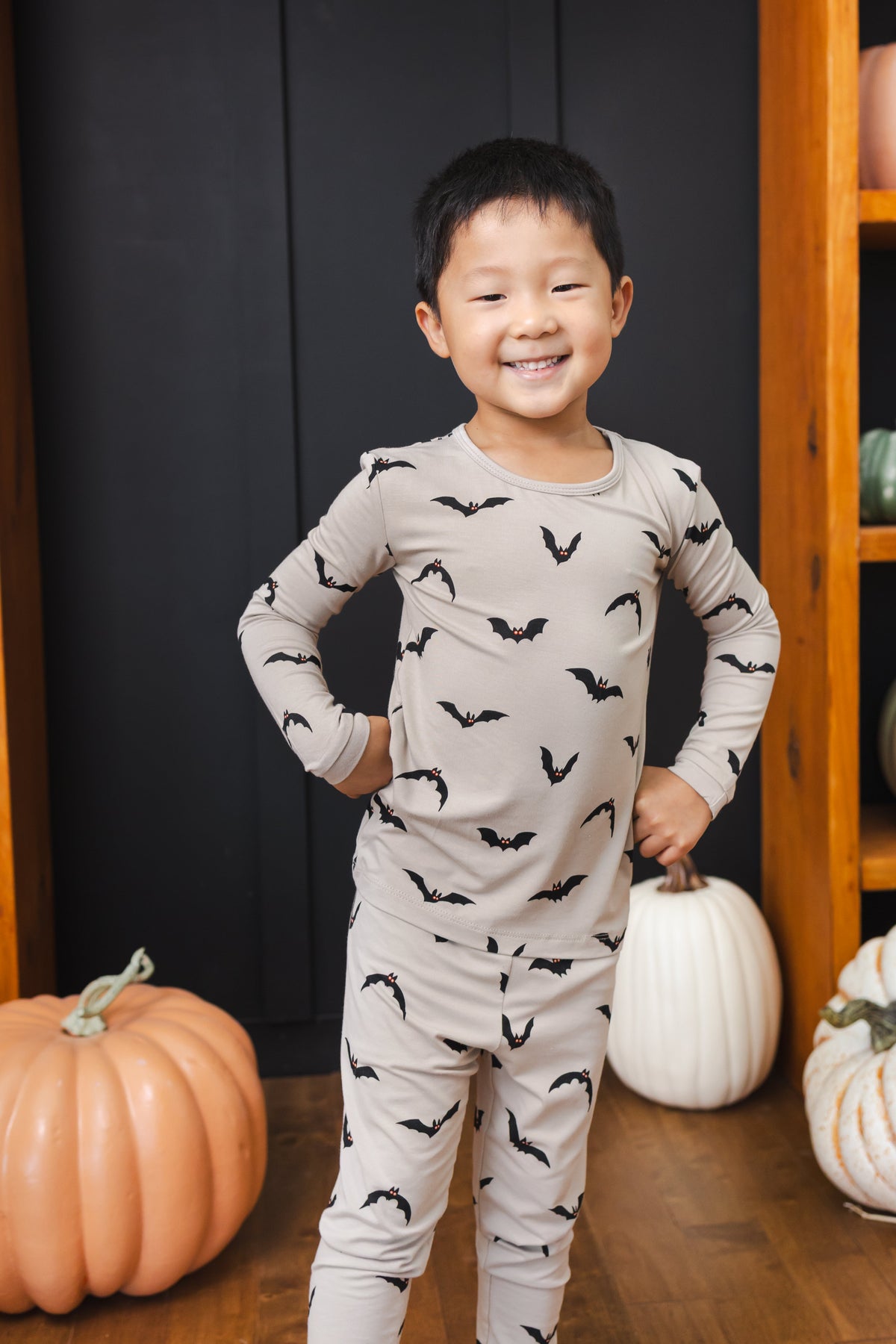Boy posing in Long Sleeve Pajamas in Bats print standing in front of pumpkin decorations