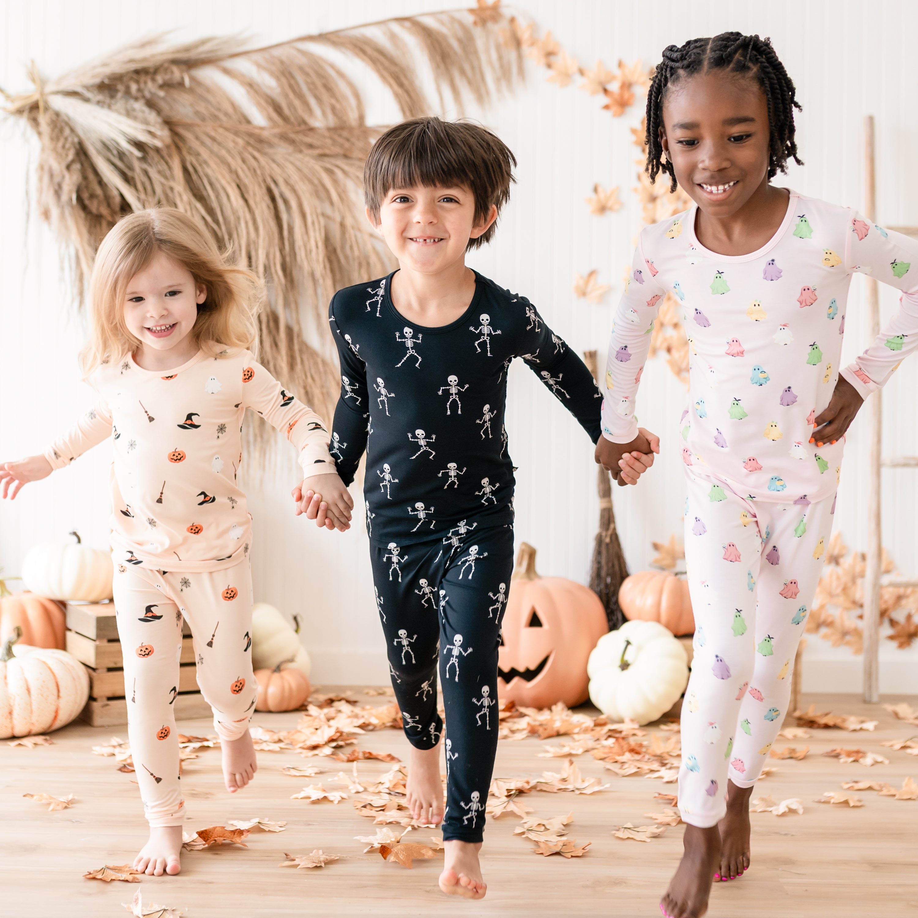Three young kids wearing Halloween Long Sleeve Toddler Pajama Set in Bewitched, Skeleton and Pastel Ghost