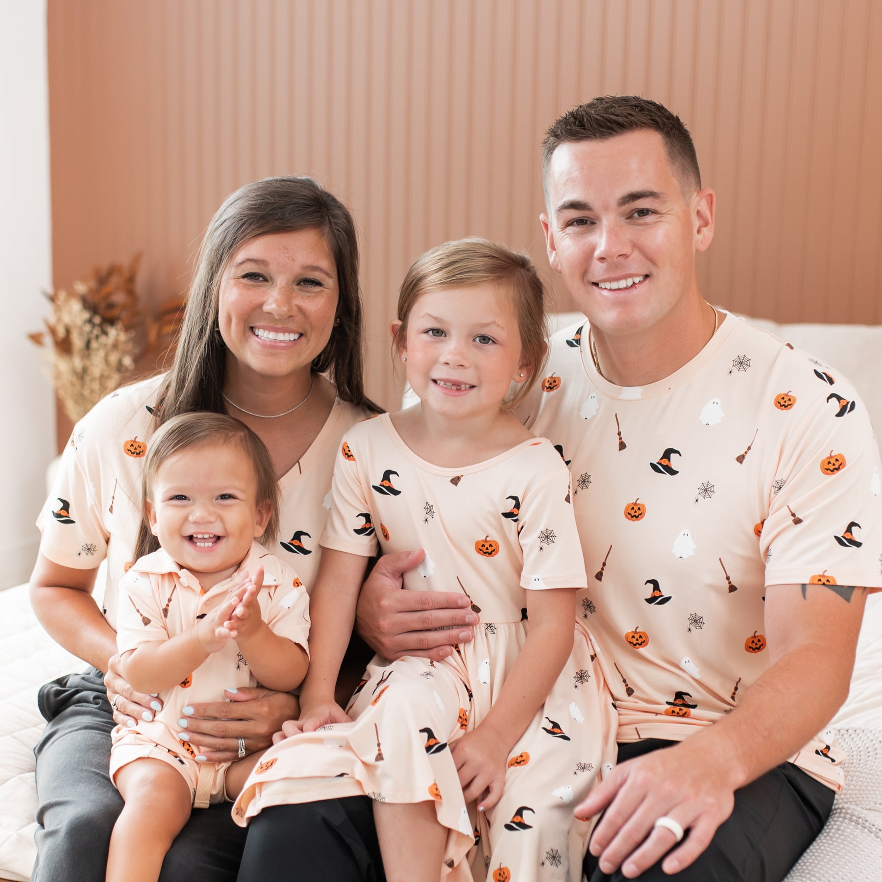 Family of four wearing matching Halloween-themed apparel sitting together.