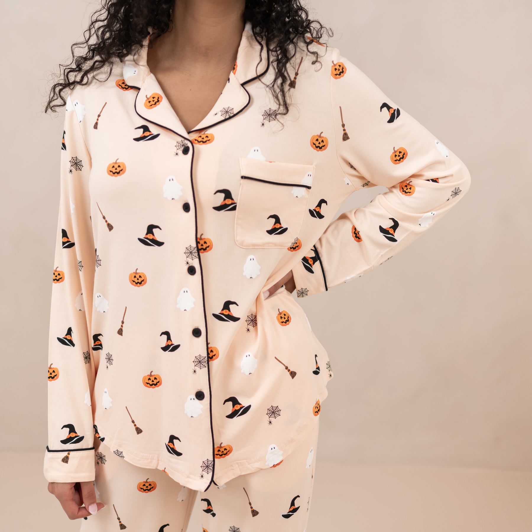 Halloween-themed pajama set with pumpkins, ghosts, and witches' hats on a neutral background.
