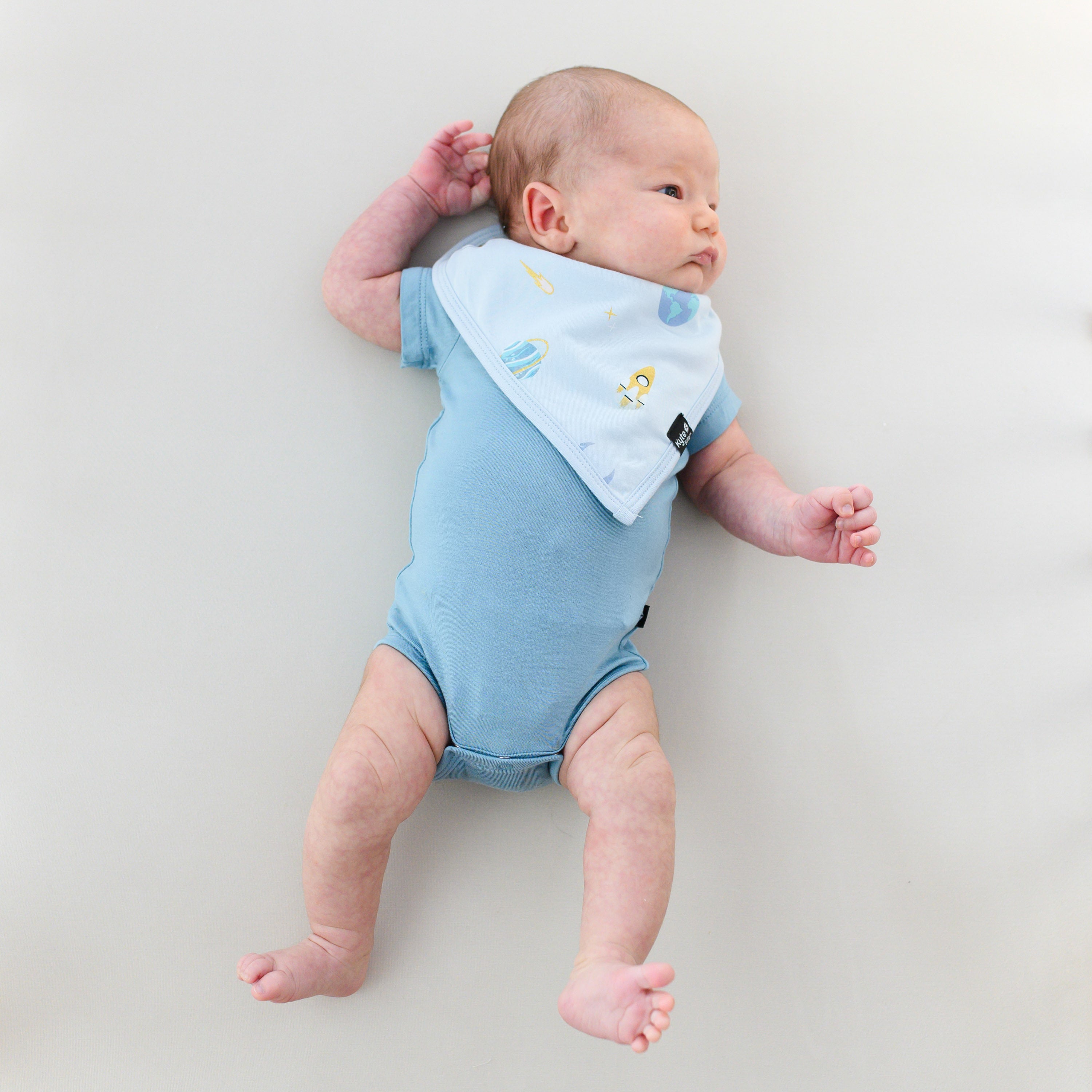 baby in a slate short sleeve bodysuit and an ice space bib