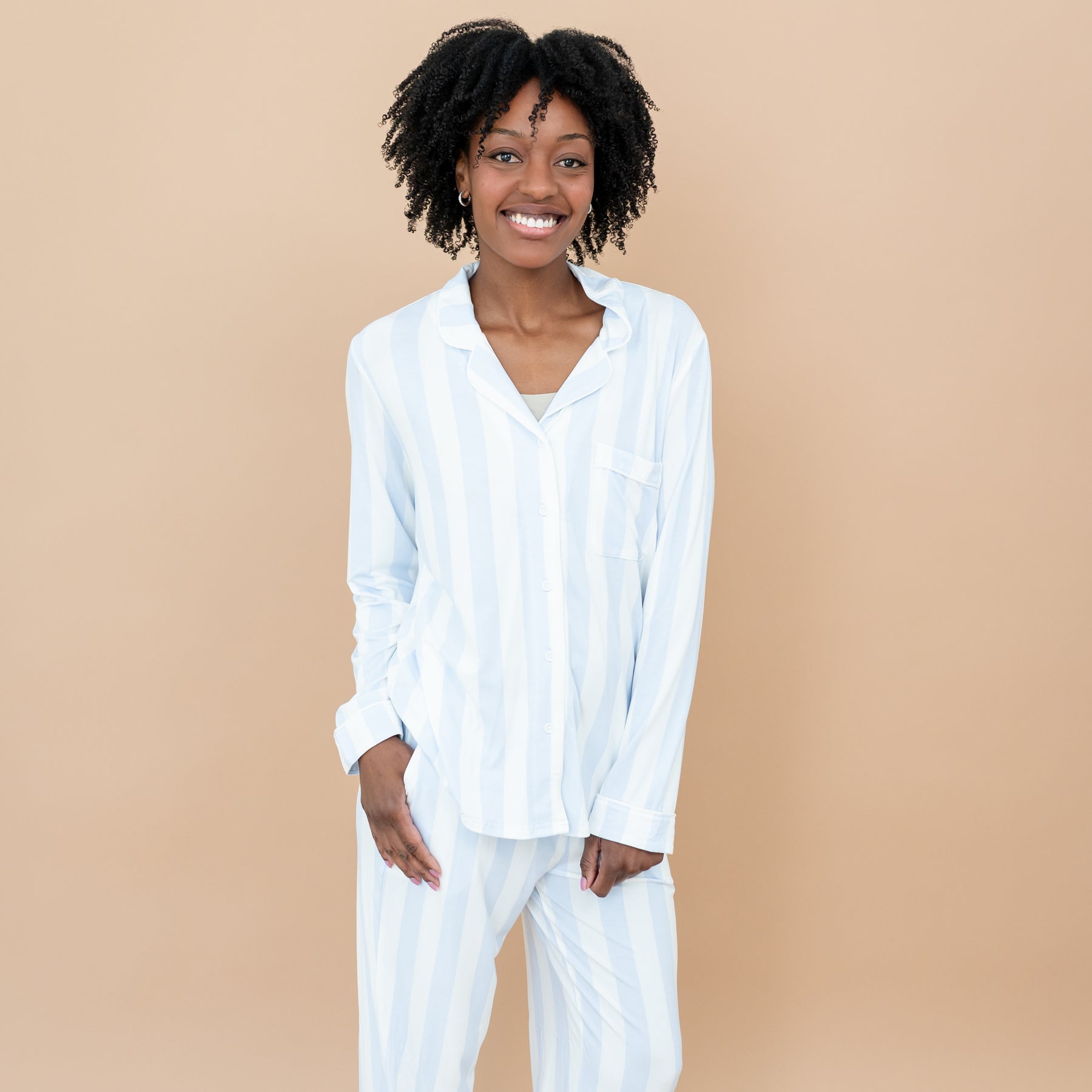 Close up of smiling female model wearing the Long-Sleeved Women's Pajama Set in Big Mist Stripe with one hand in pants pocket