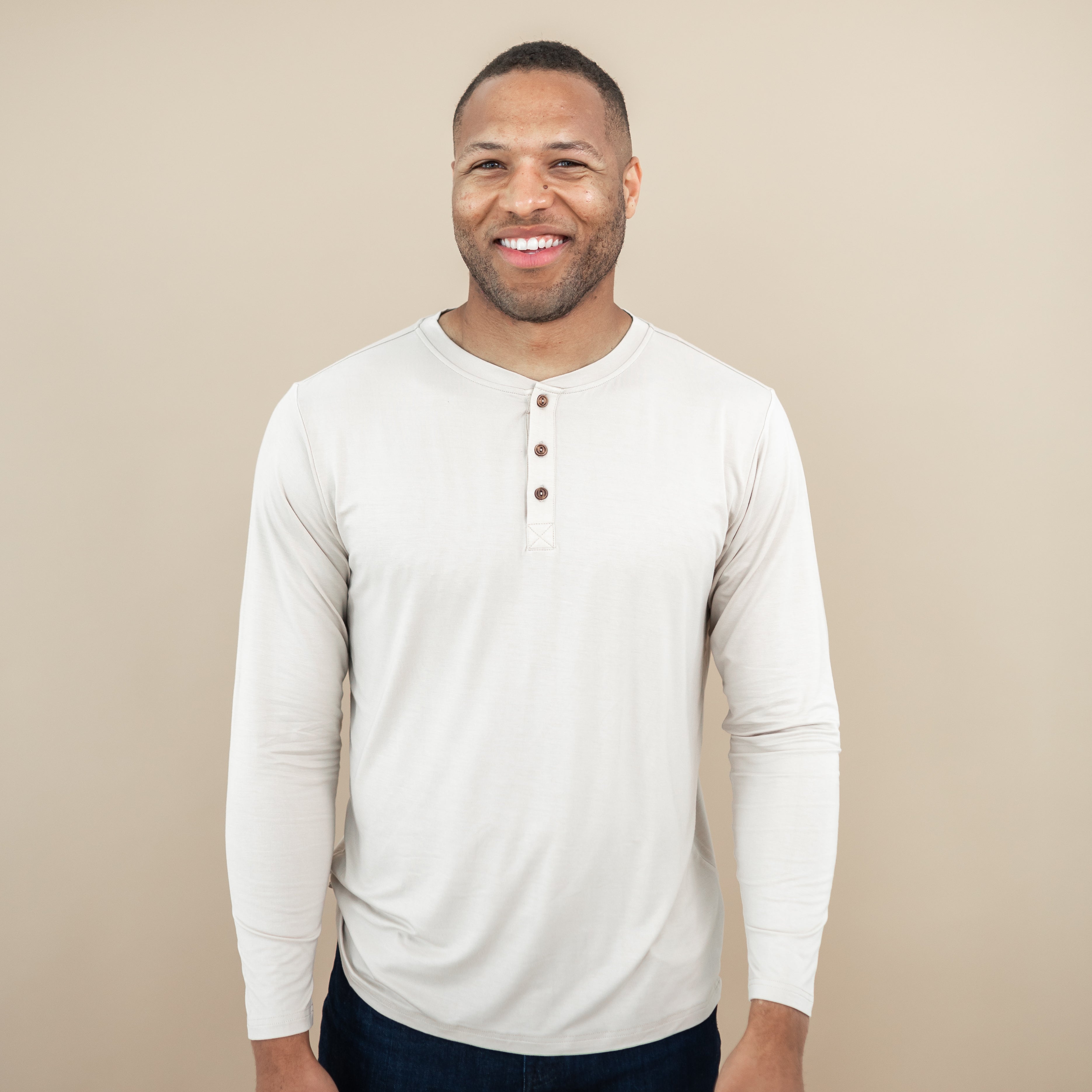 Smiling male model wearing the Men's Long Sleeve Henley Top in Bisque