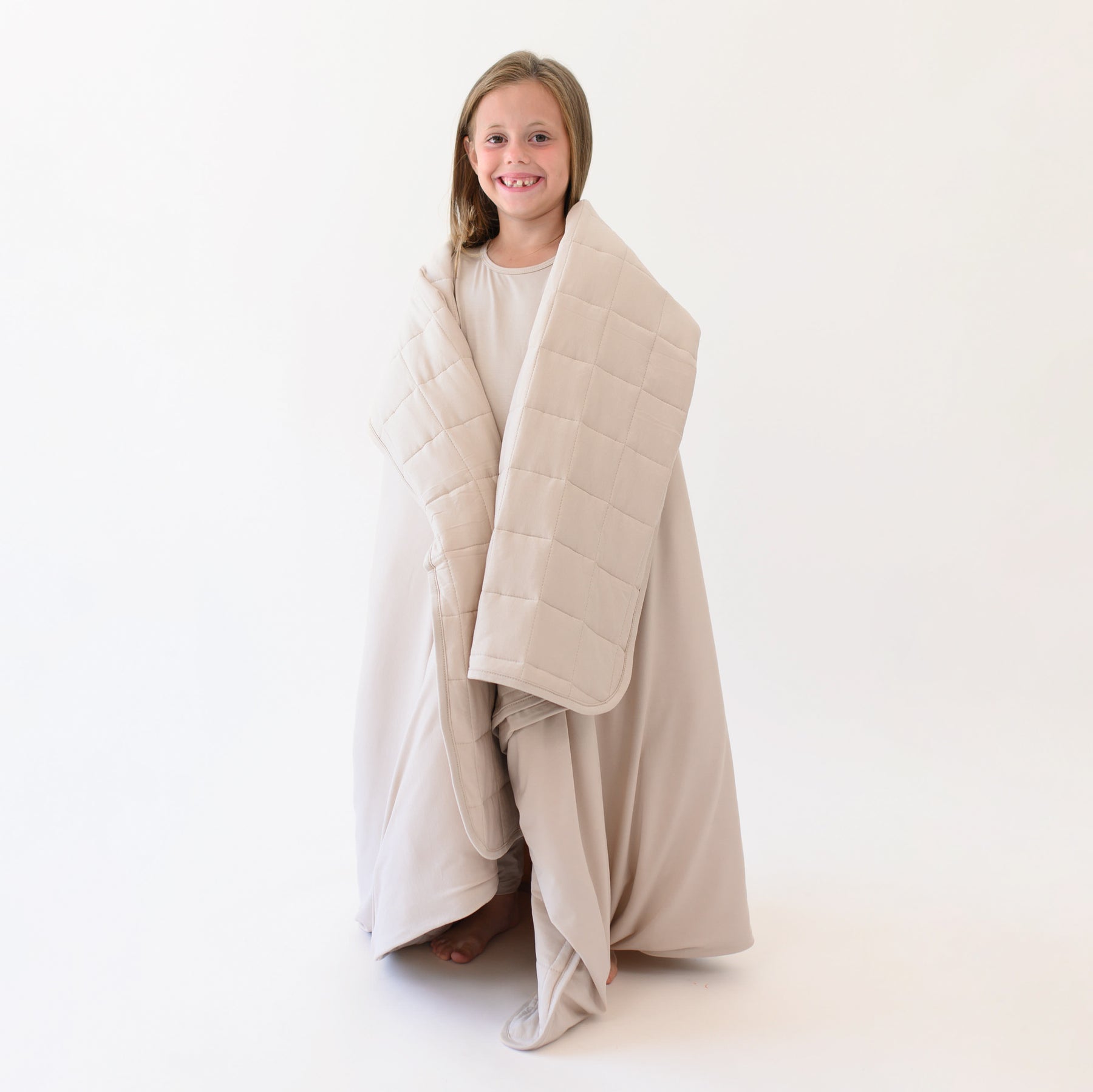 Smiling young girl model standing wrapped in the Youth Blanket in Bisque 2.5