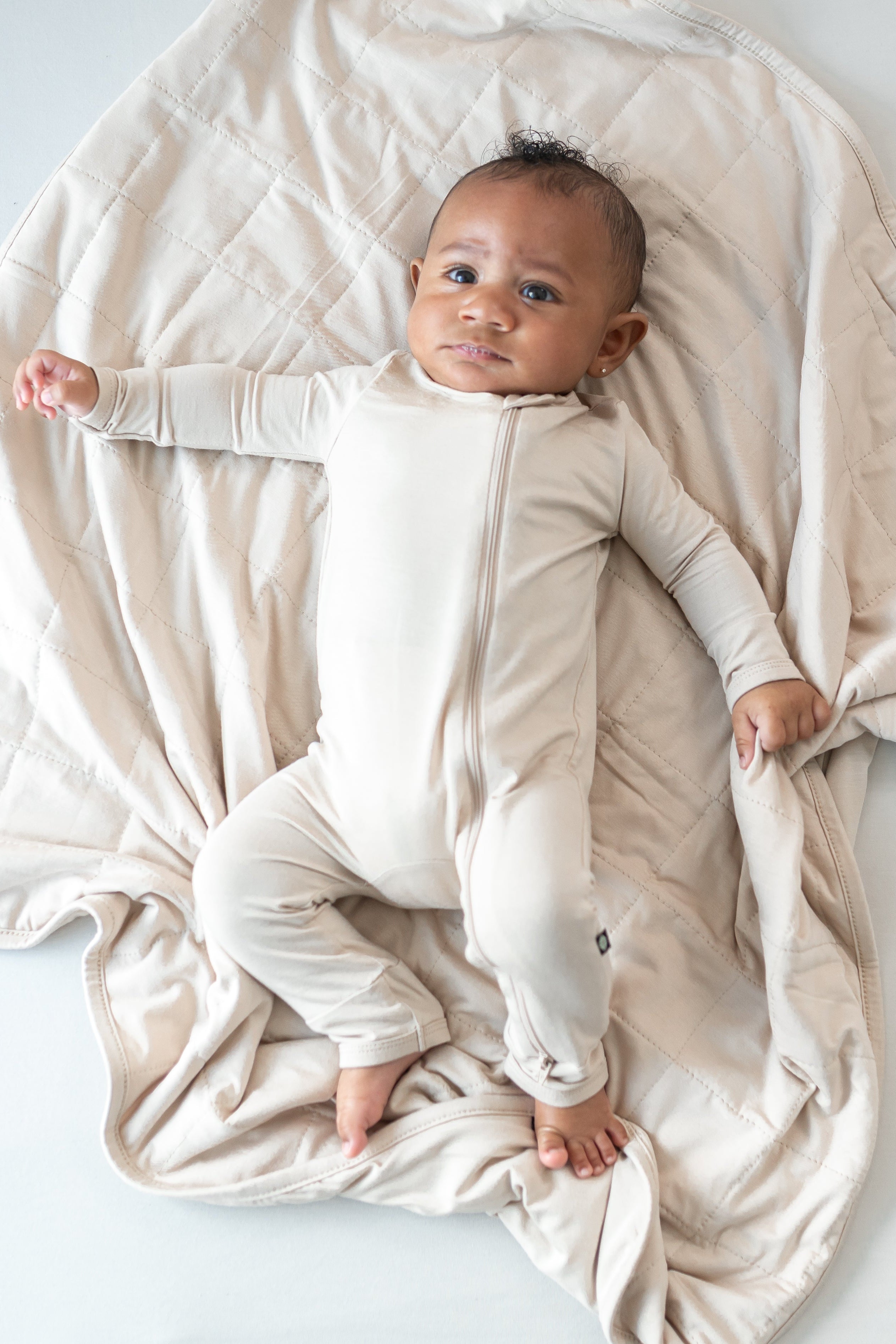 Infant wearing Bisque neutral romper pajamas laying on Baby Blanket in Bisque TOG 1.0 