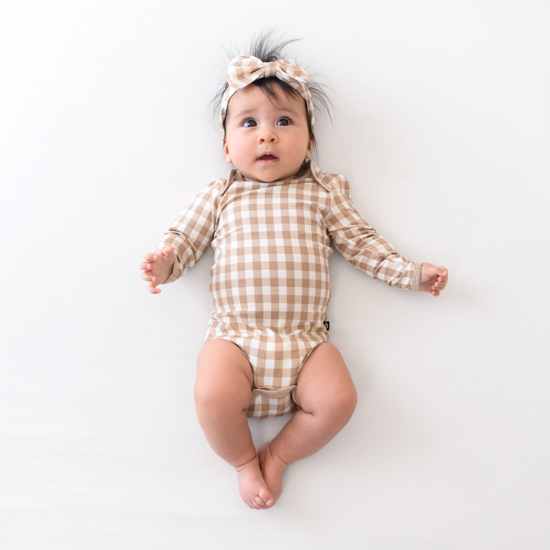 Infant wearing holiday Bow Headband and Long Sleeve Bodysuit in Gingham Bisque