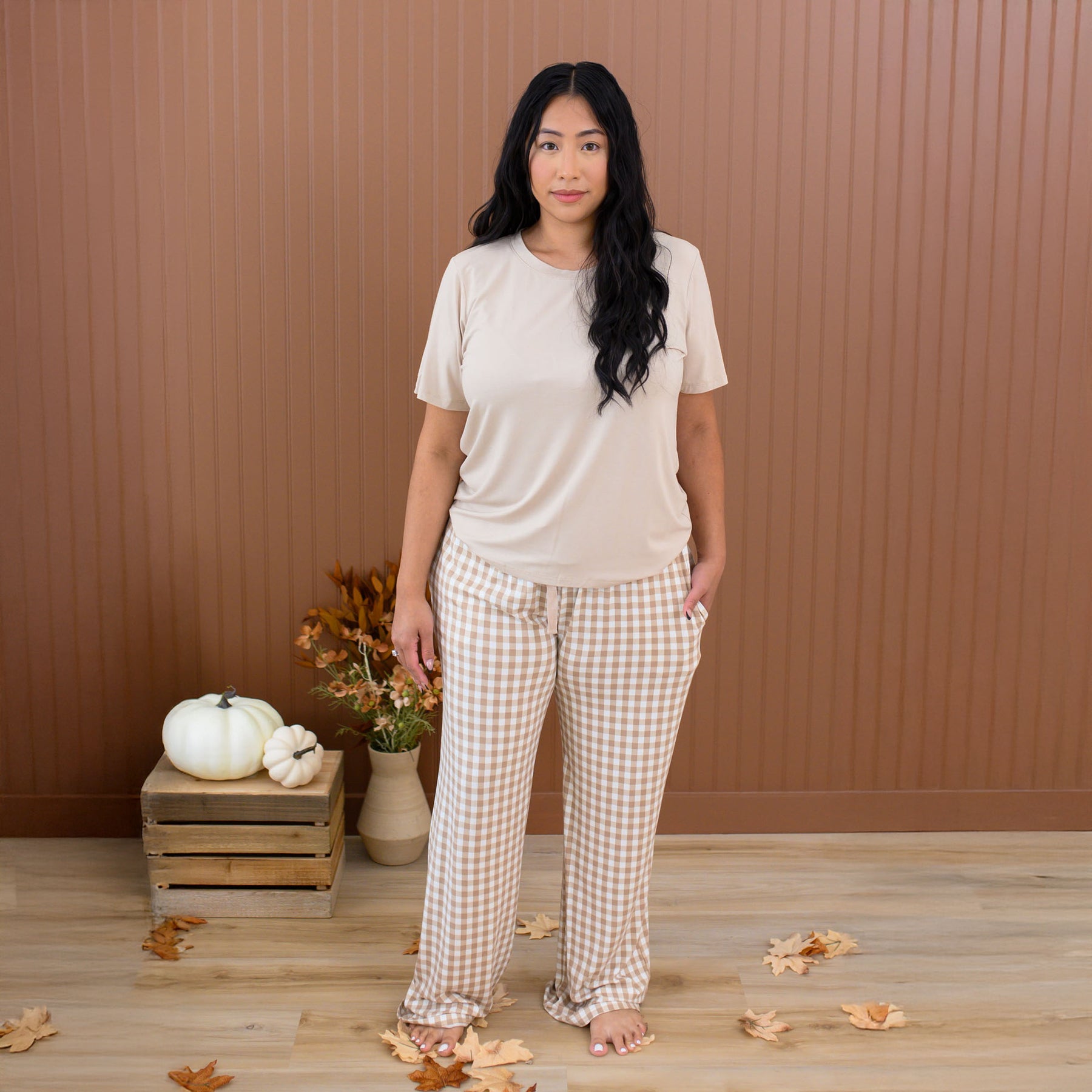 Female wearing the Women's Lounge Pants in Gingham Bisque paired with a Women's Crew Neck Tee in Bisque in front of a fall backdrop