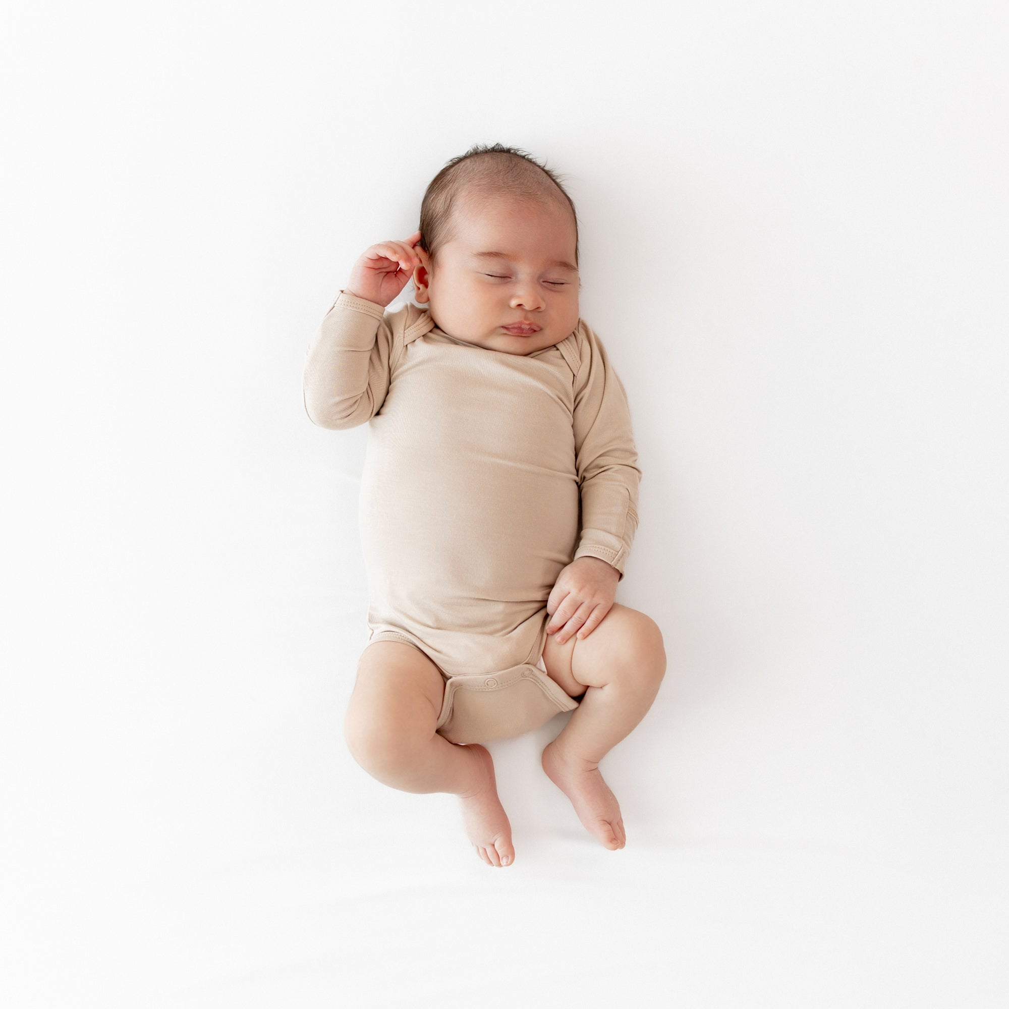 Sleeping newborn wearing the Long Sleeve Bodysuit in Bisque