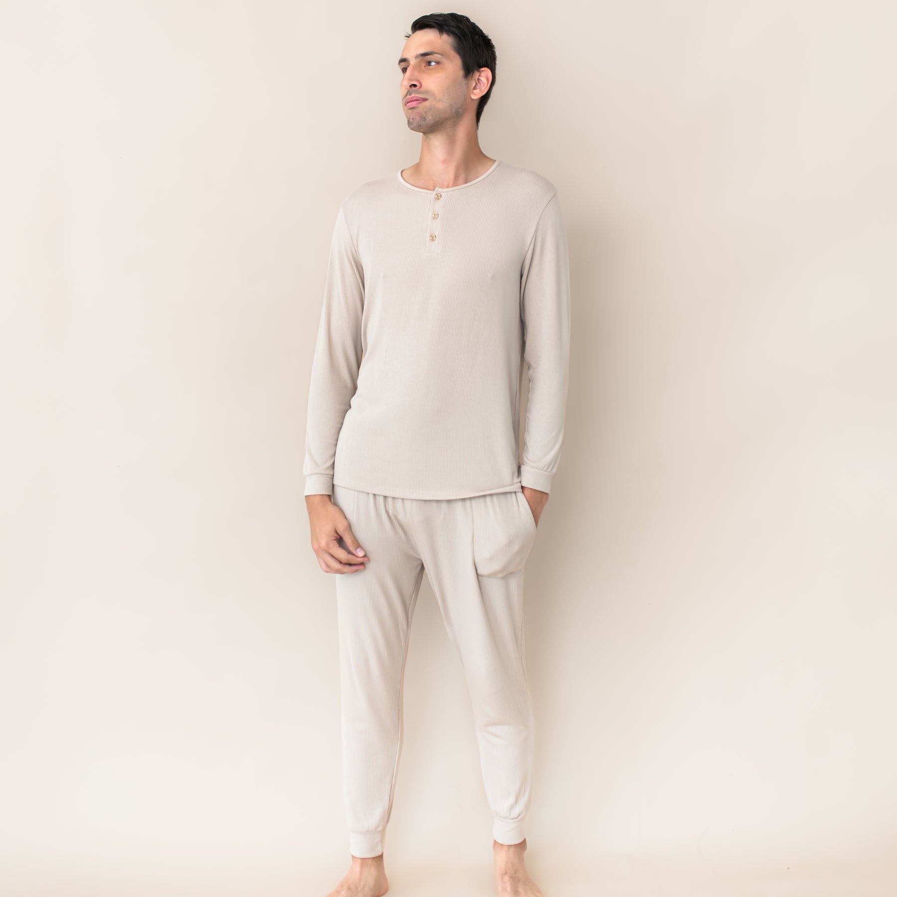 Male model wearing the Men's Ribbed Henley Set in Bisque in front of a cream colored background