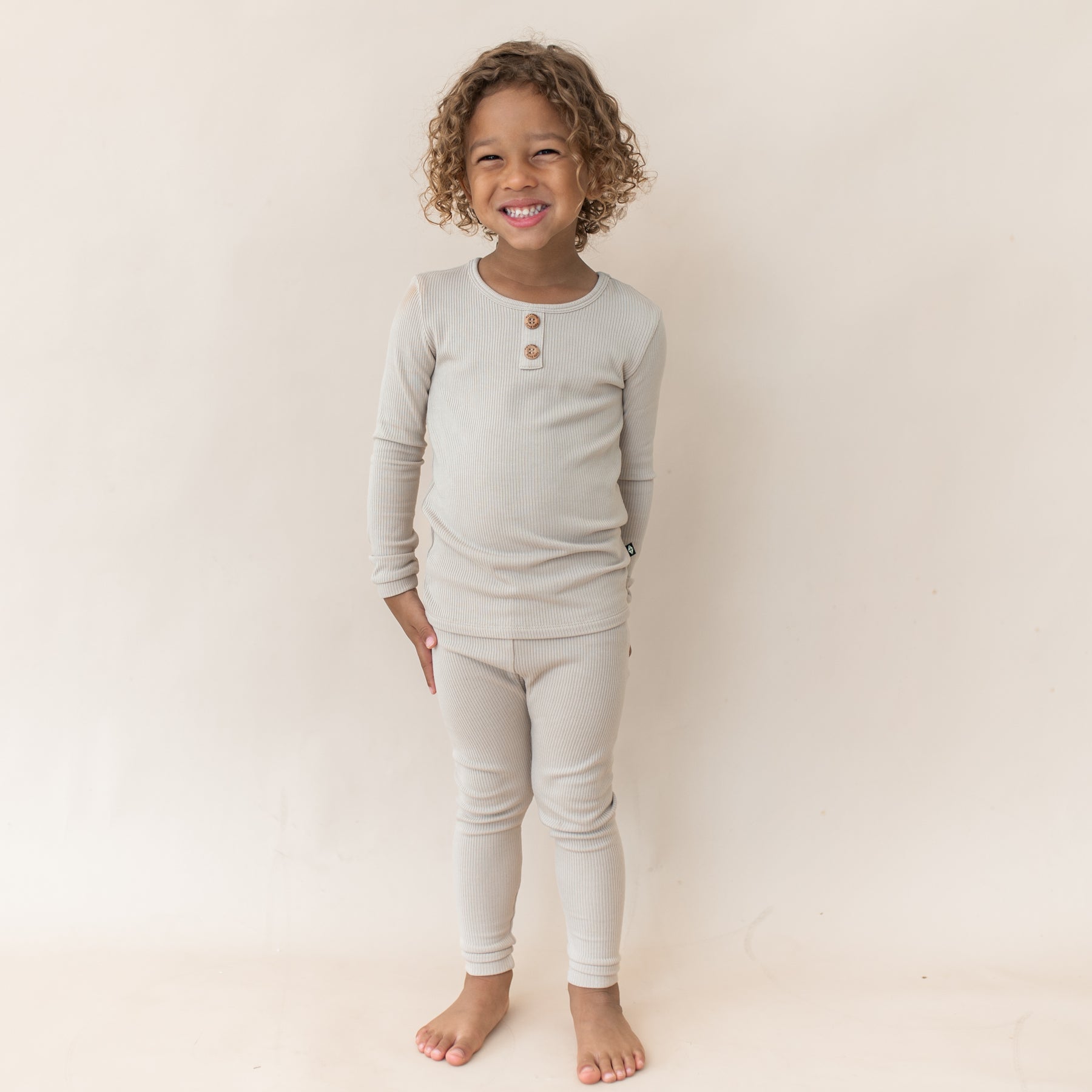 Smiling young girl wearing the Ribbed Henley Set in Bisque