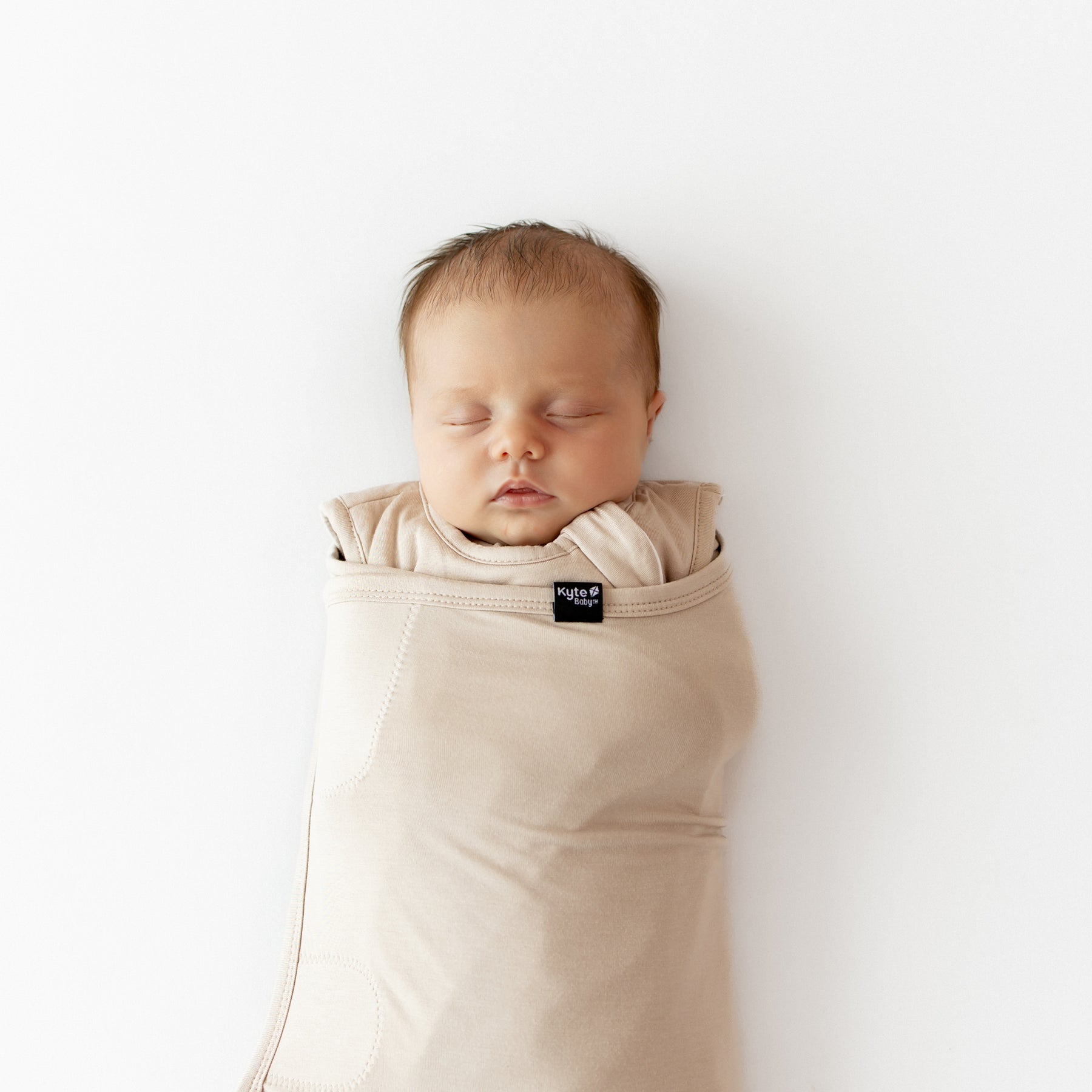 Close up of a sleeping newborn swaddled in the Sleep Bag Swaddler in Bisque 1.0