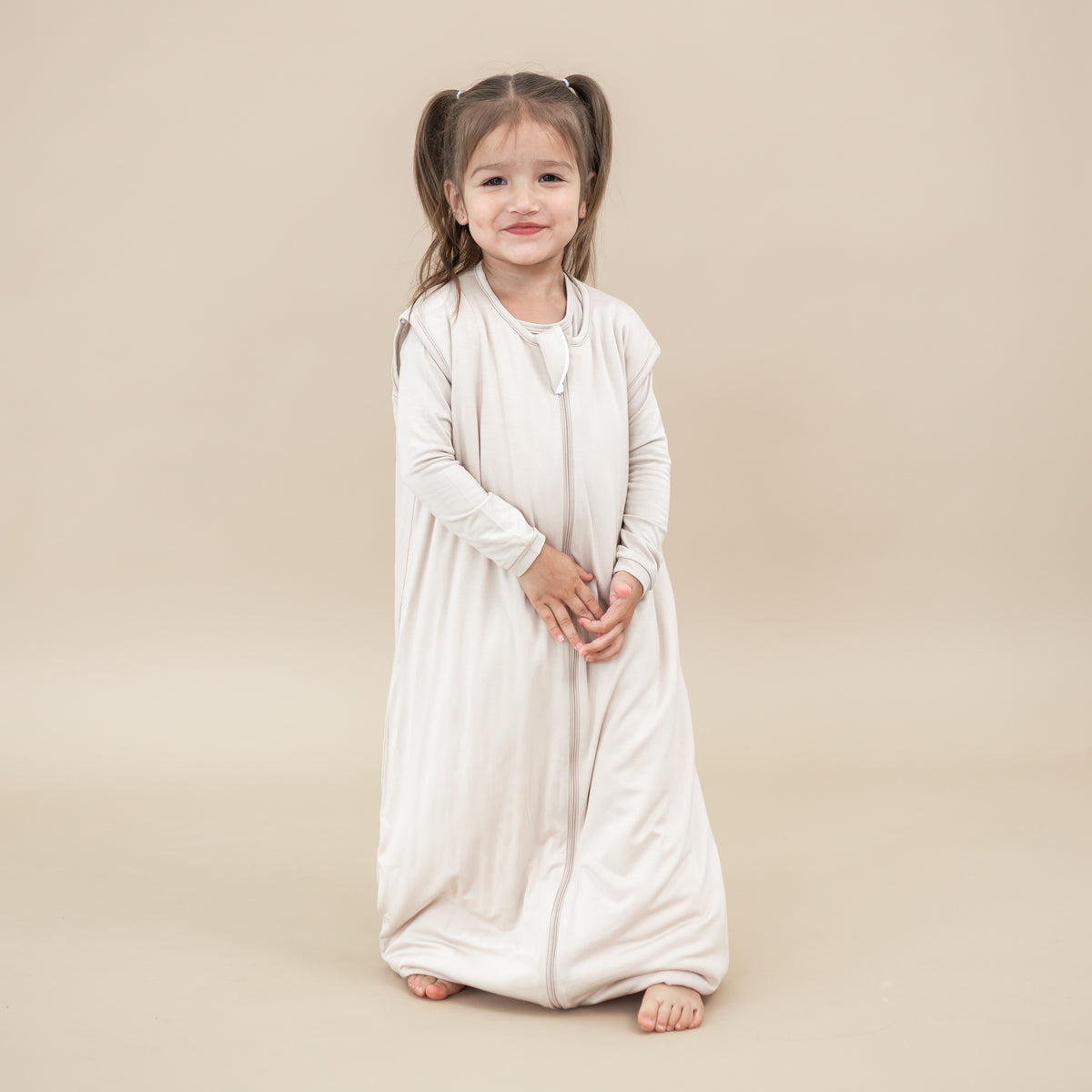Young girl model wearing the Sleep Bag Walker in Bisque 1.0 with matching long sleeve toddler pajamas on underneath
