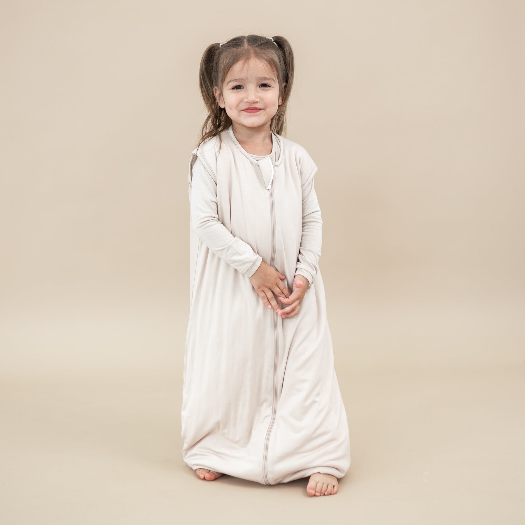 Young girl model wearing the Sleep Bag Walker in Bisque 1.0 with matching long sleeve toddler pajamas on underneath
