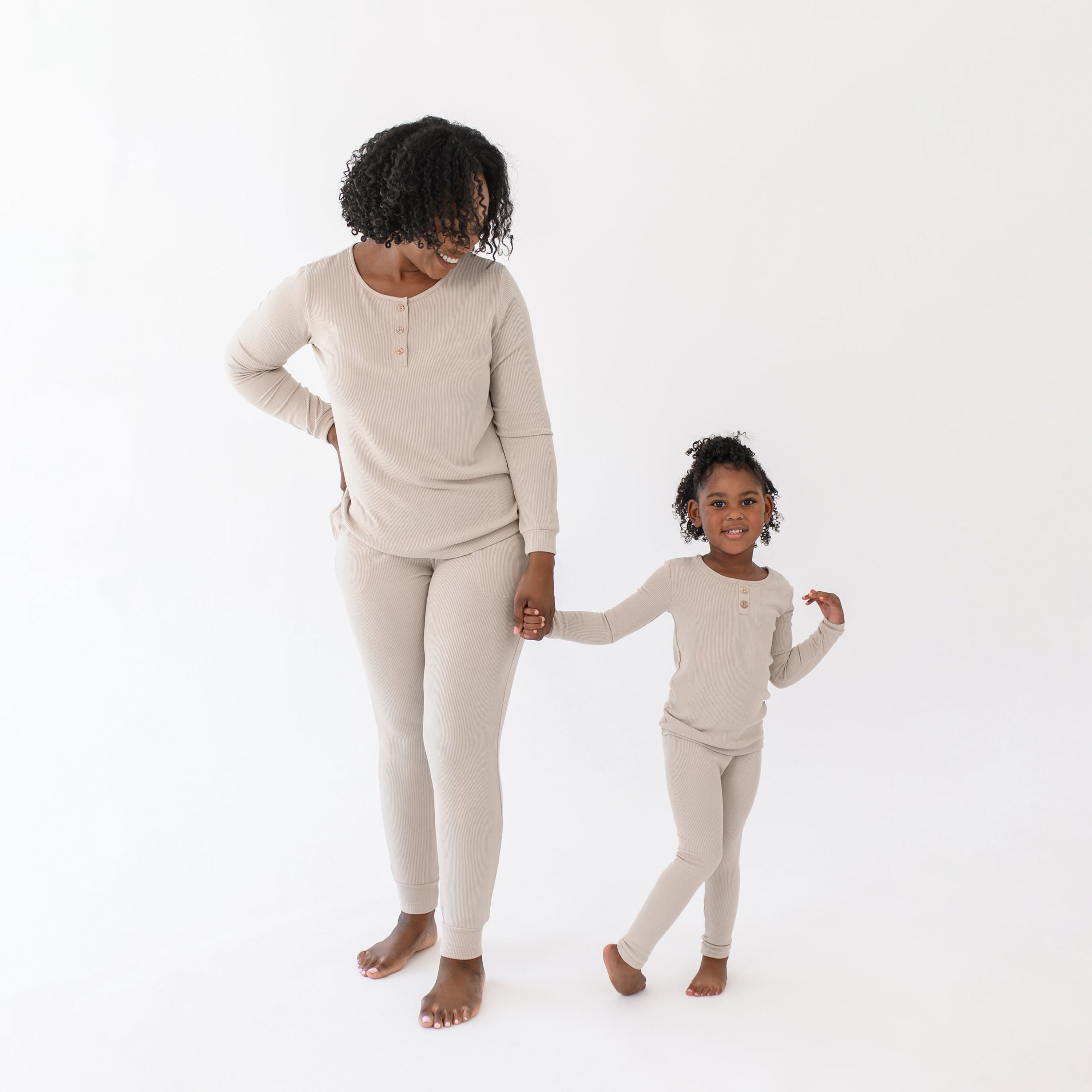 Mother and daughter standing side by side holding hands matching in the Ribbed Henley Sets in Bisque