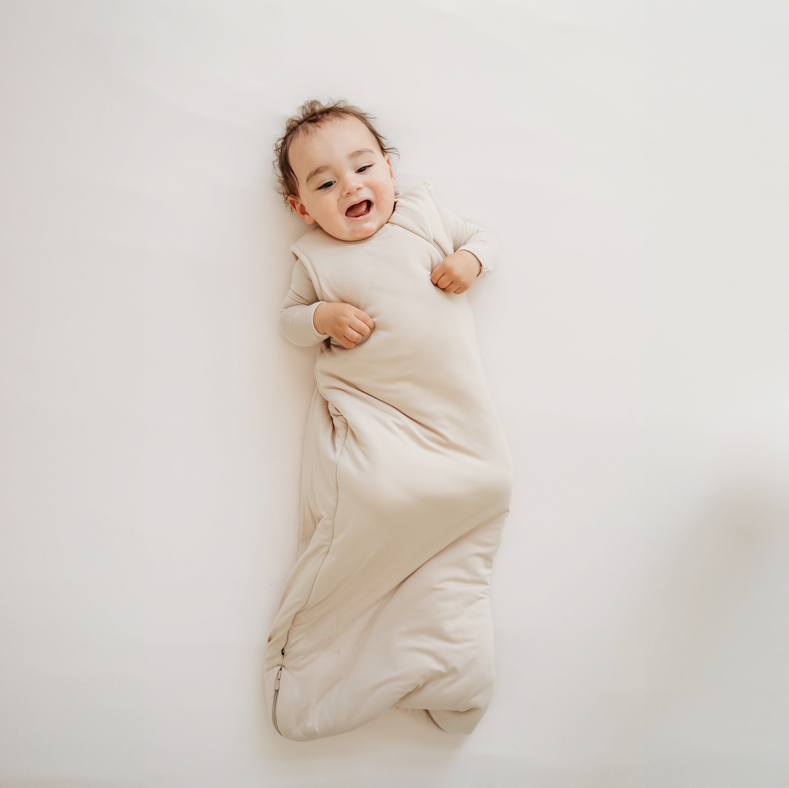 Young toddler wearing the Sleep Bag in Bisque 2.5 with matching long sleeve romper on underneath