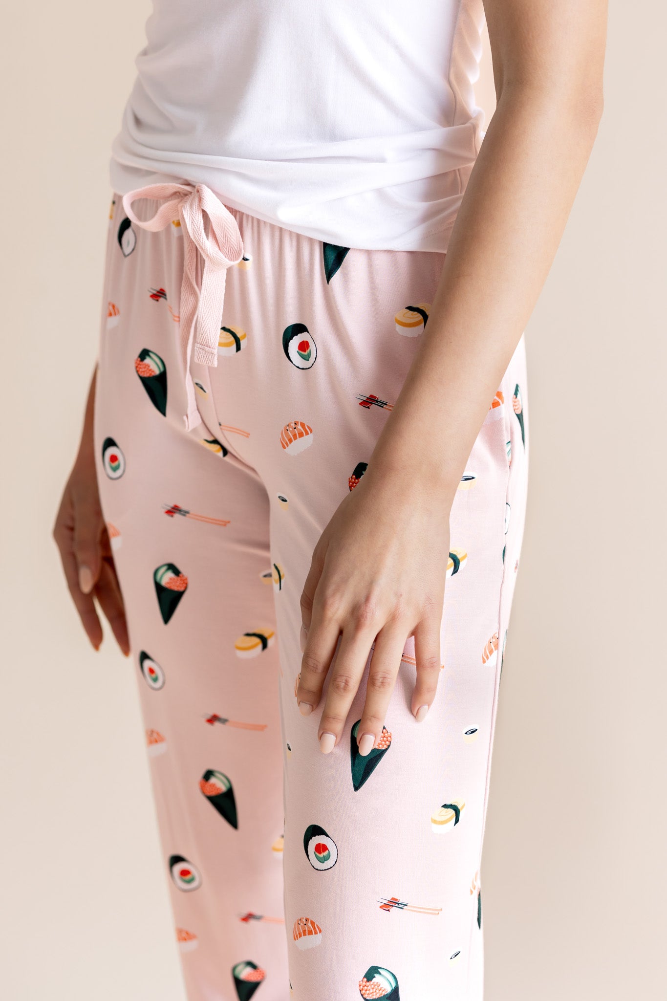 Model in pink Women's Lounge Pants with drawstring in Sushi print under white camisole on a beige background