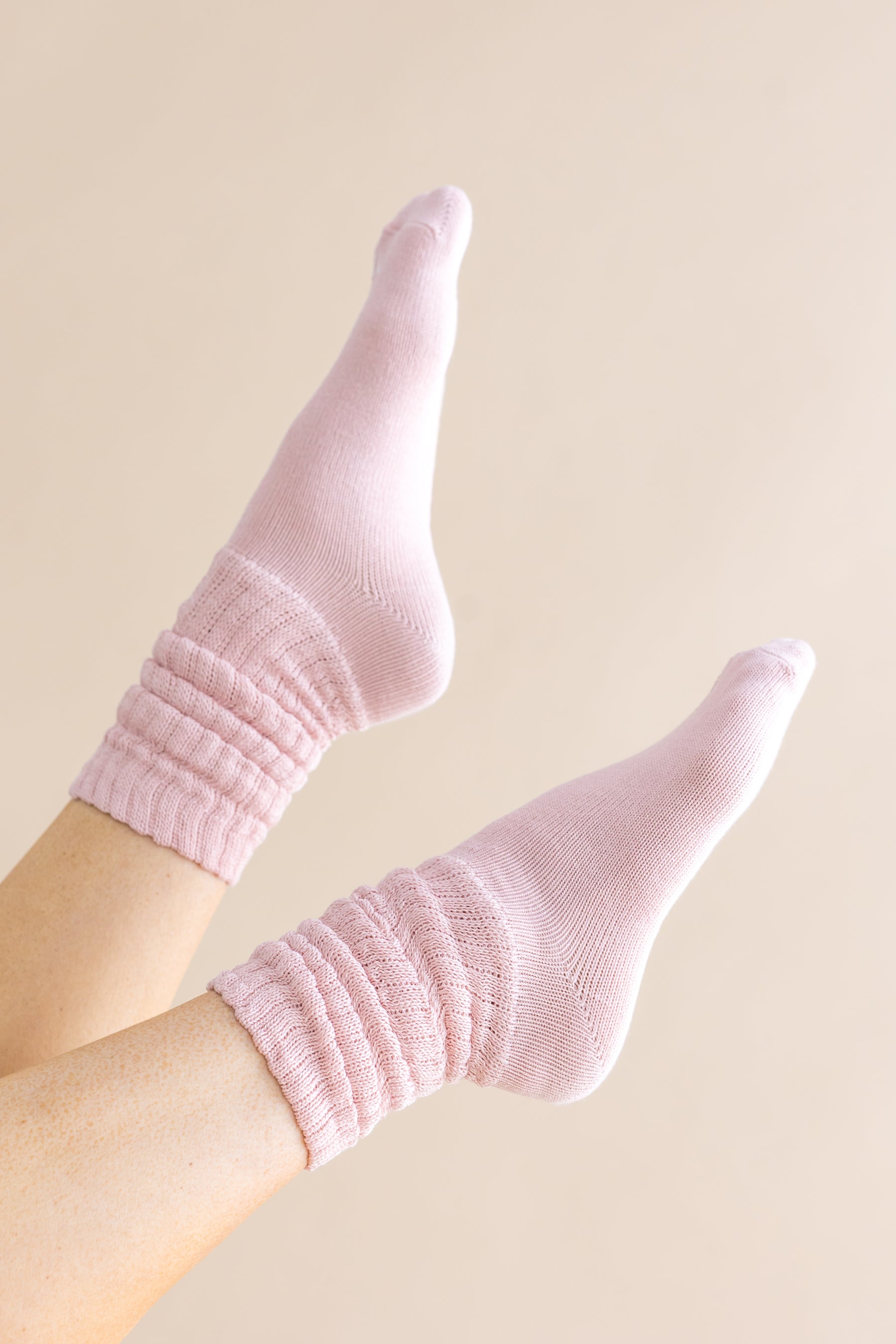 Adult Scrunch Socks in Blush shown on a models feet in the air against a light cream background