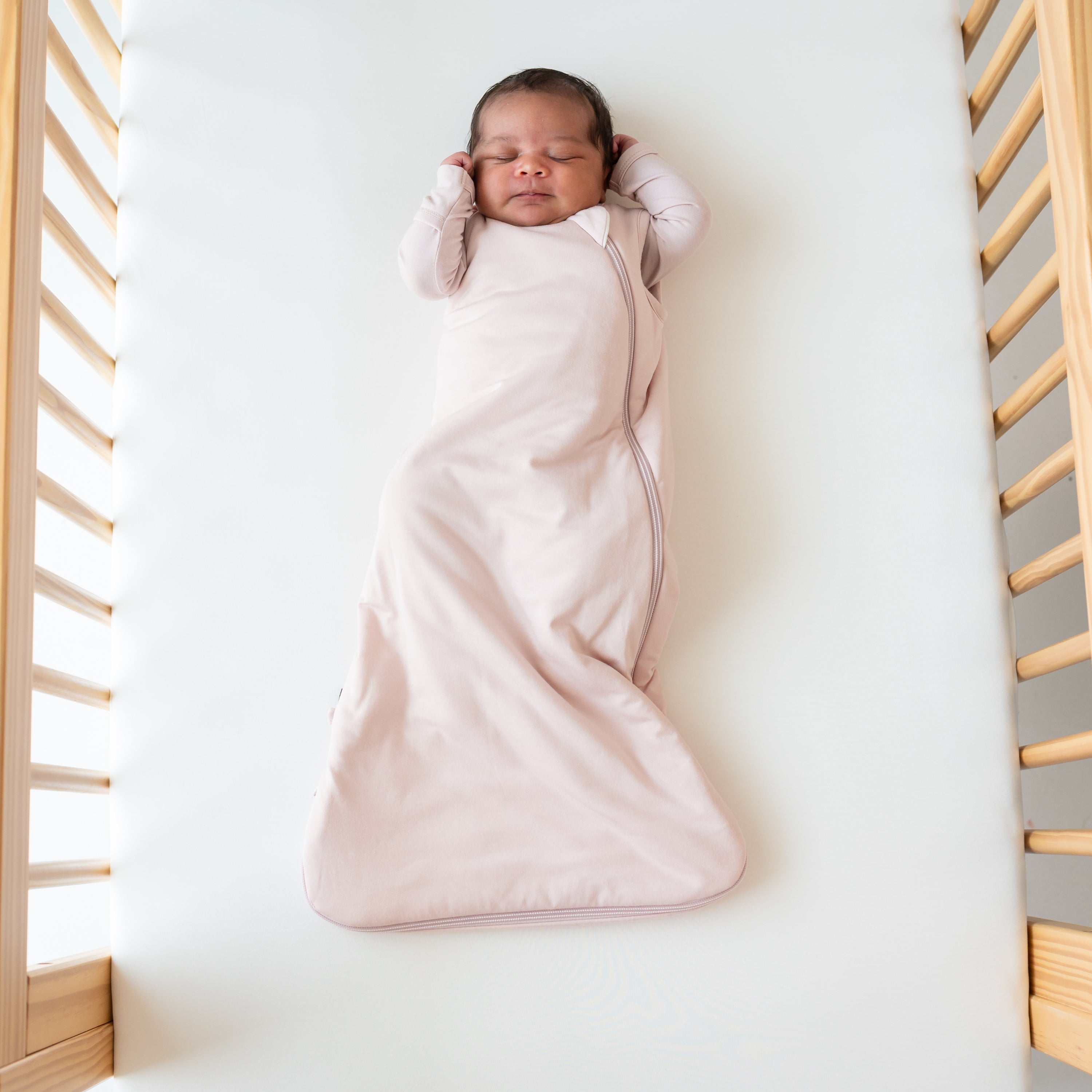 Baby sleeping in Blush Sleep bag in a crib