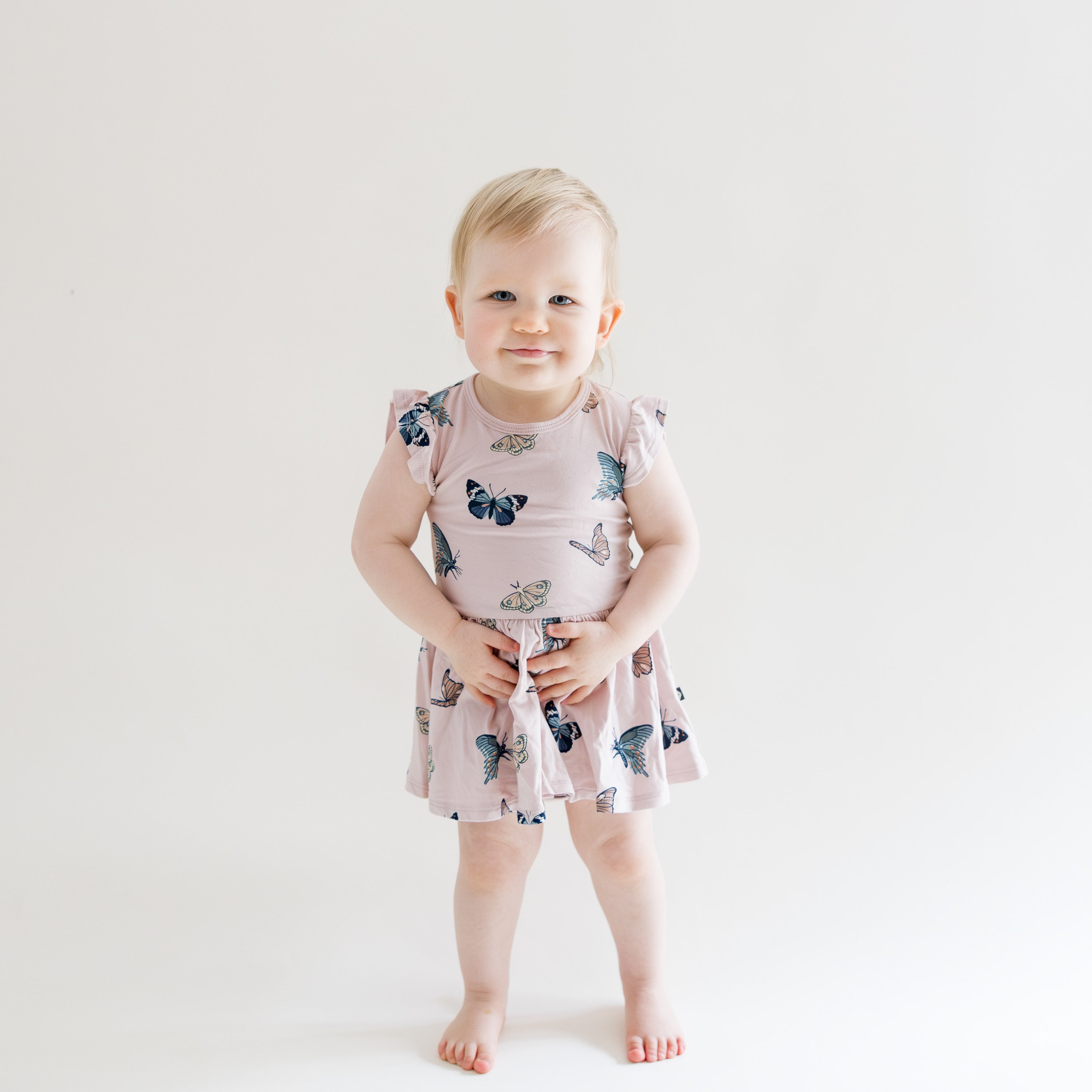 Toddler standing wearing Twirl Bodysuit Dress in Blush Butterfly