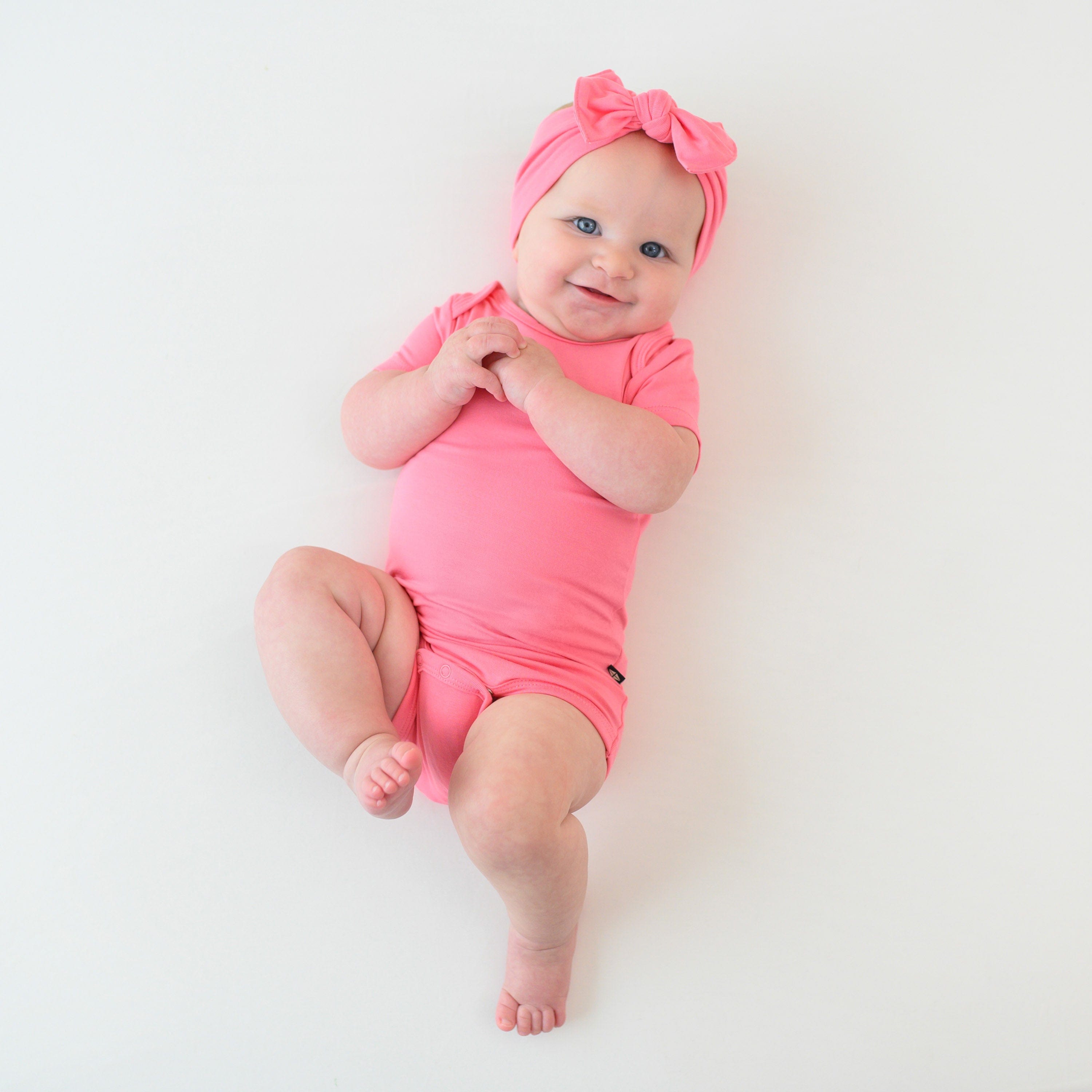 baby in bodysuit and bow in gauva