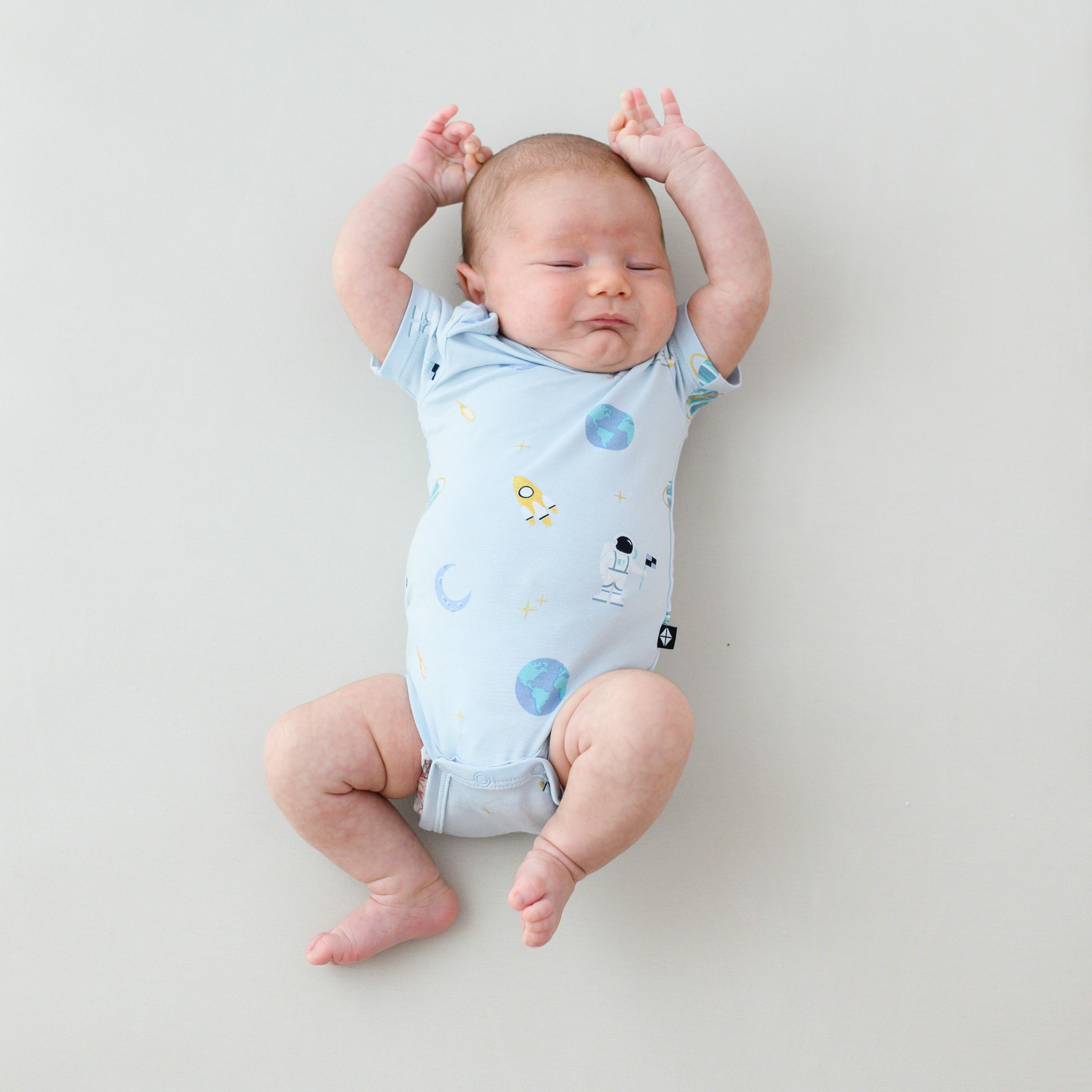 baby stretching arms wearing ice space short sleeve bodysuit