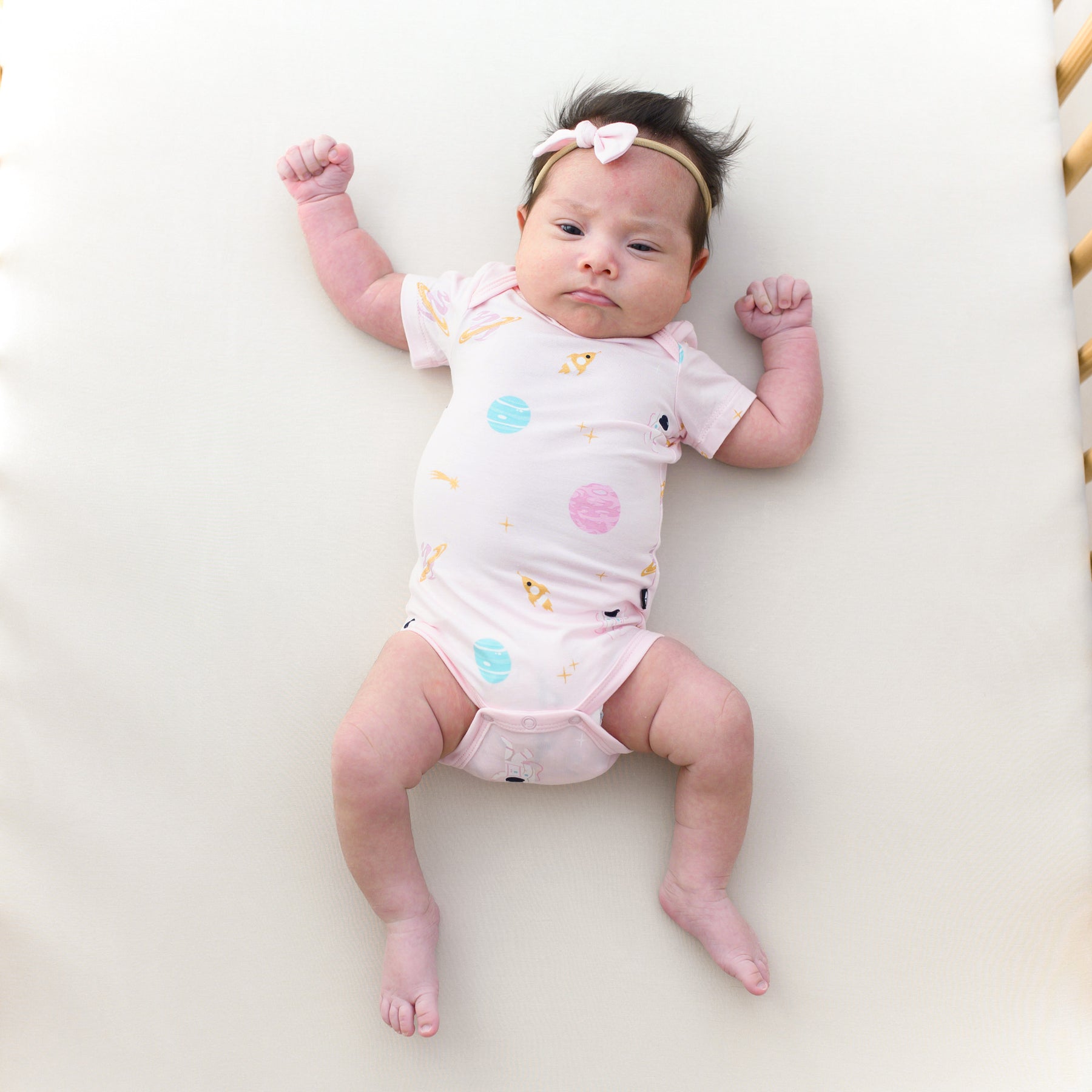 baby in a crib wearing sakura space short sleeve bodysuit