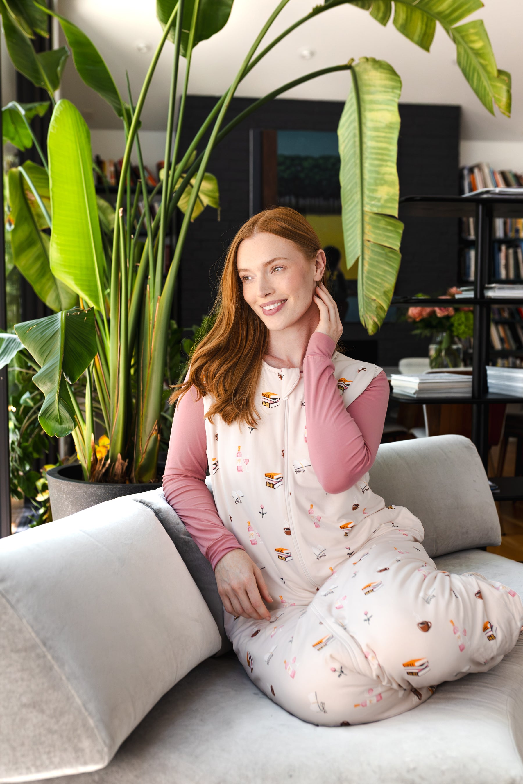 Modal posing in Adult Sleep Bag Walker in Book Club print sitting on a sofa