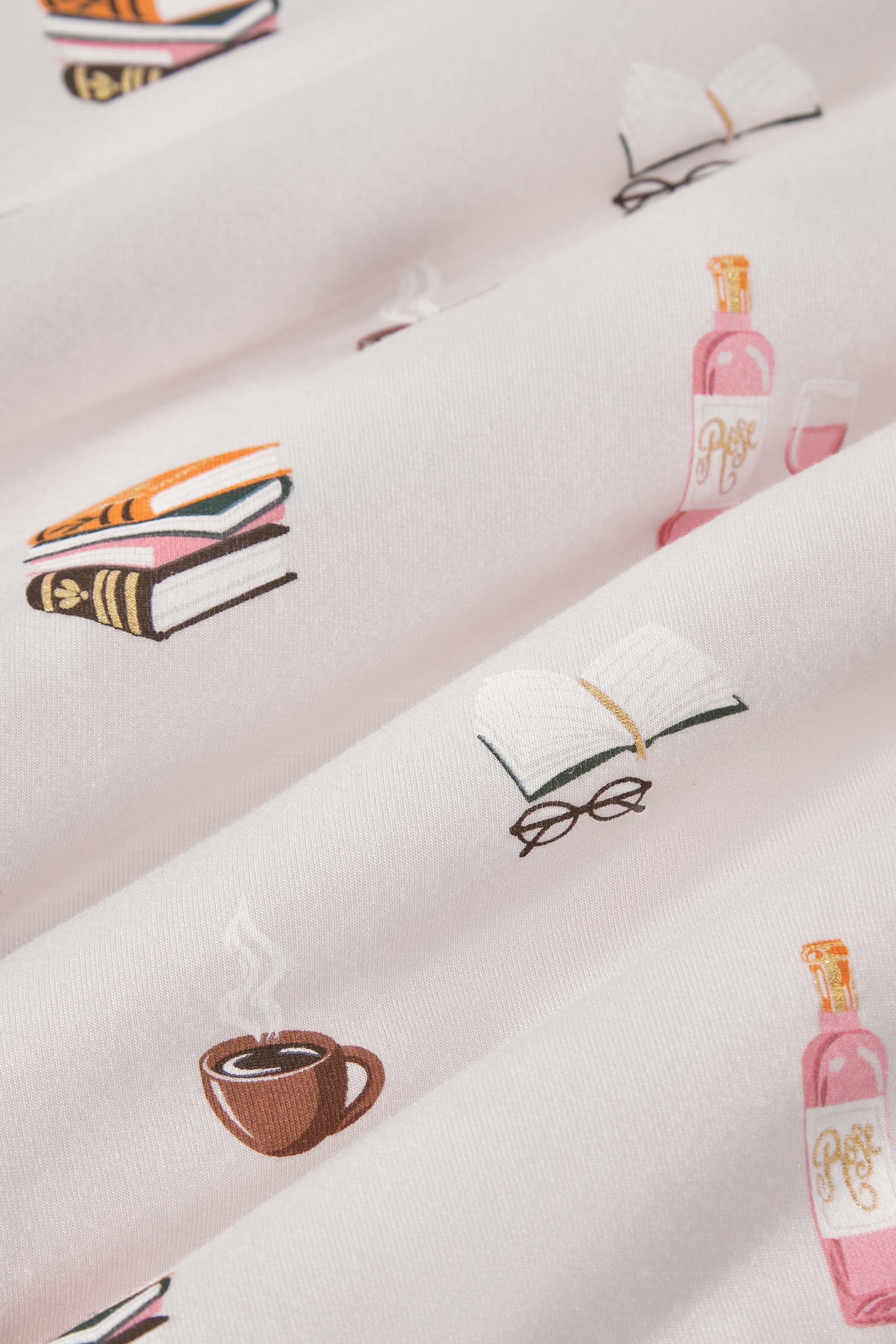 Close up of pink fabric with books with, specs and coffee cup print on it 