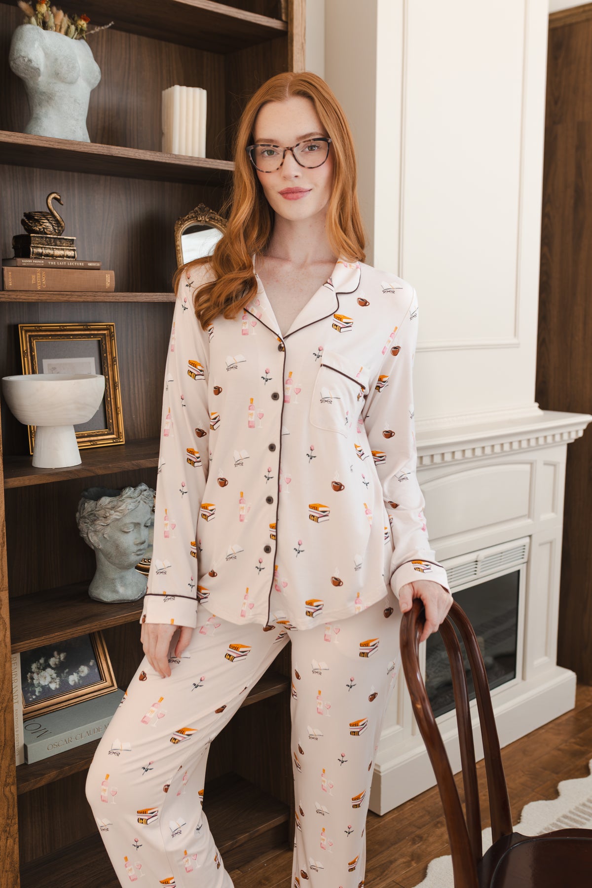 Modal wearing Long-Sleeved Women's Pajama Set in Book Club print posing in a living room