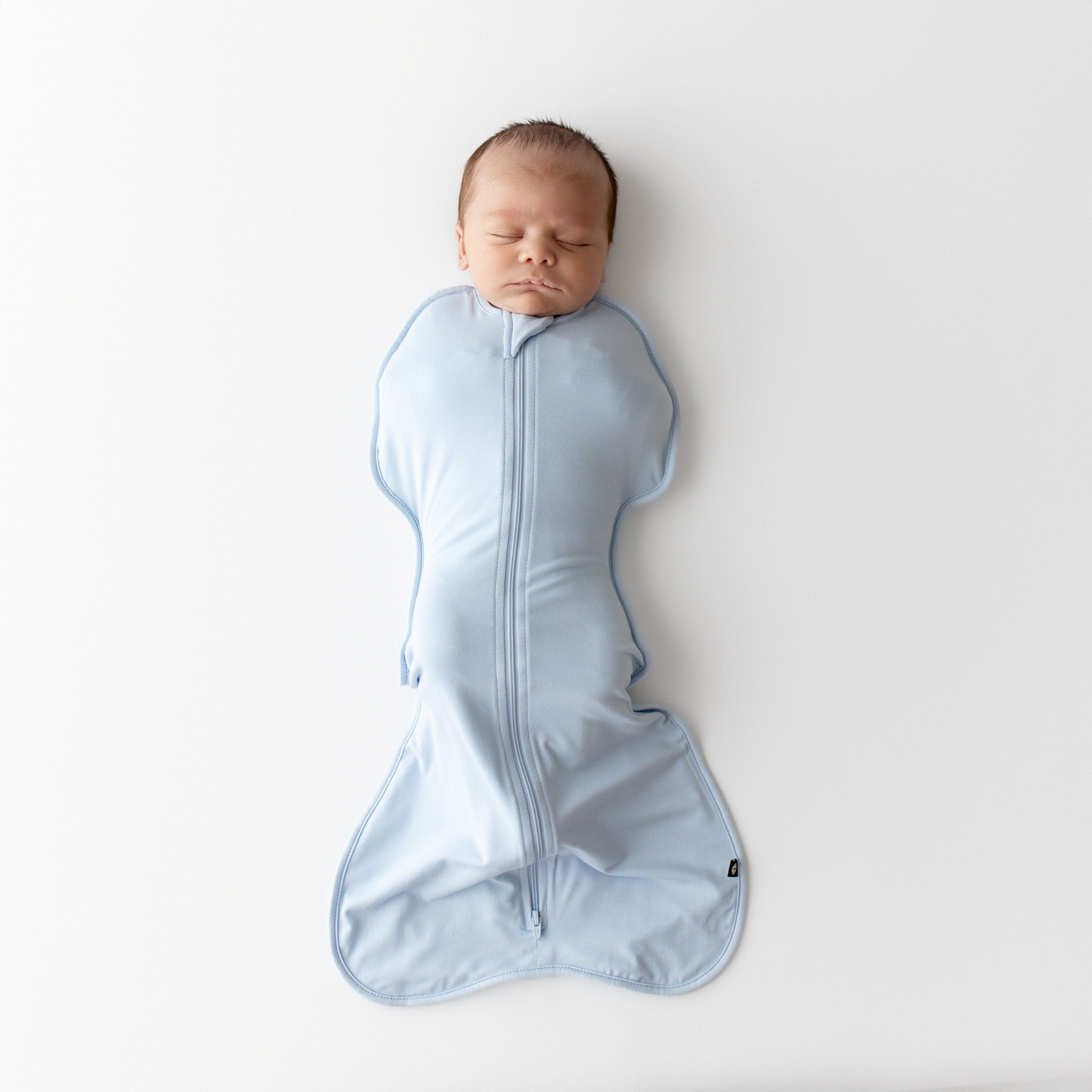Newborn baby wrapped in a blue swaddle bag on a white background