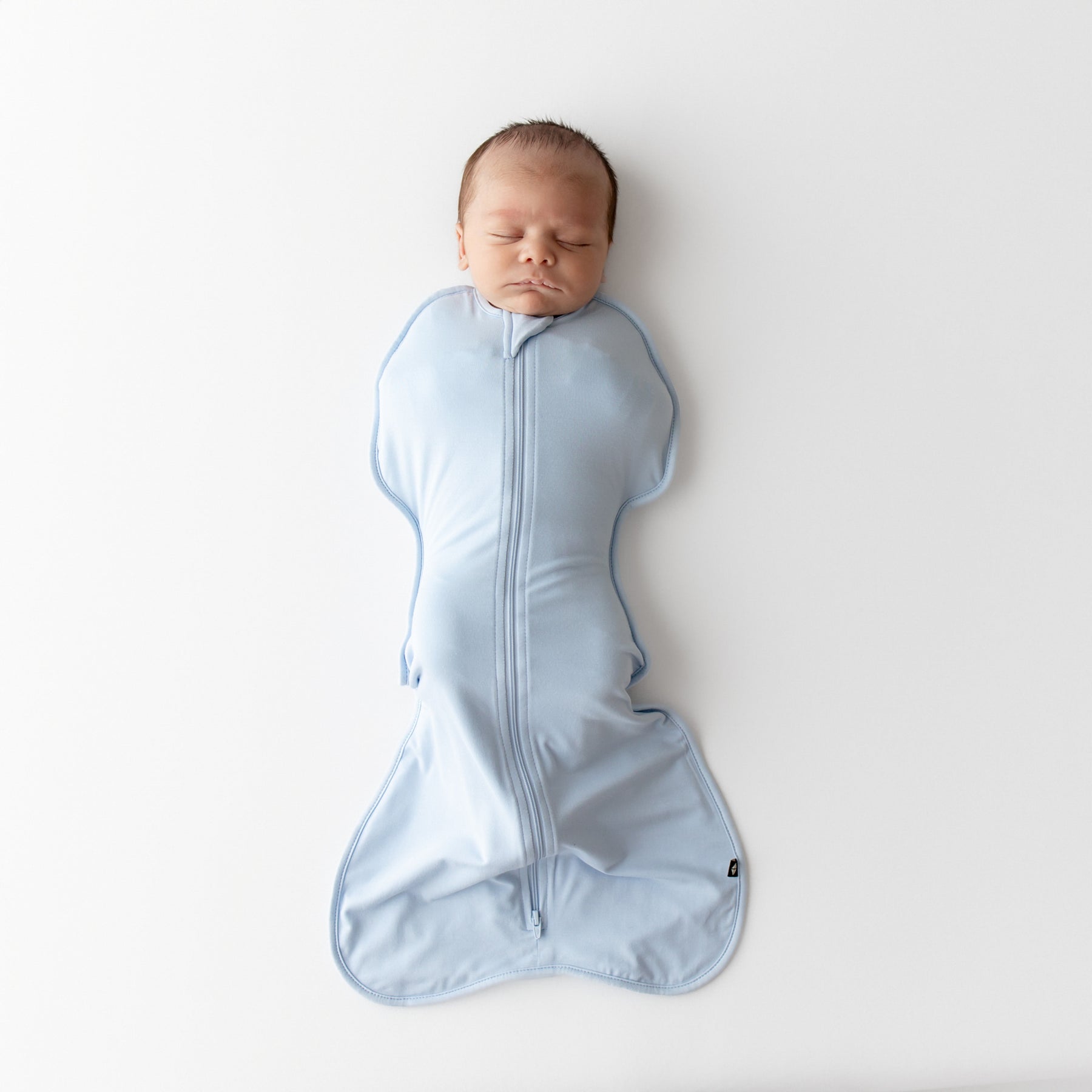 Newborn baby wrapped in a blue swaddle bag on a white background