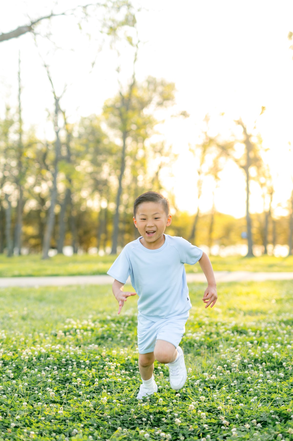Young boy running through a grass field wearing the Short Sleeve Jogger Set in Breeze