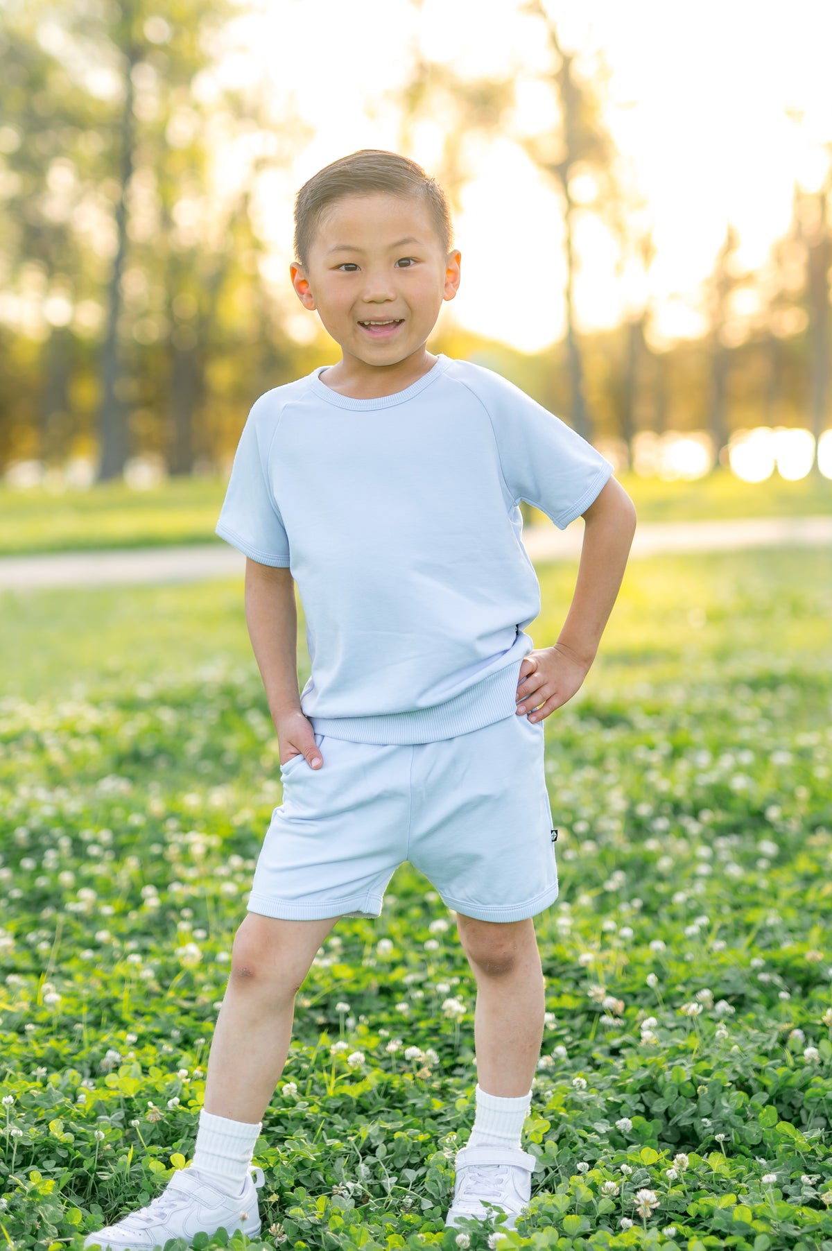 Young boy posing standing in a grass field wearing the Short Sleeve Jogger Set in Breeze 