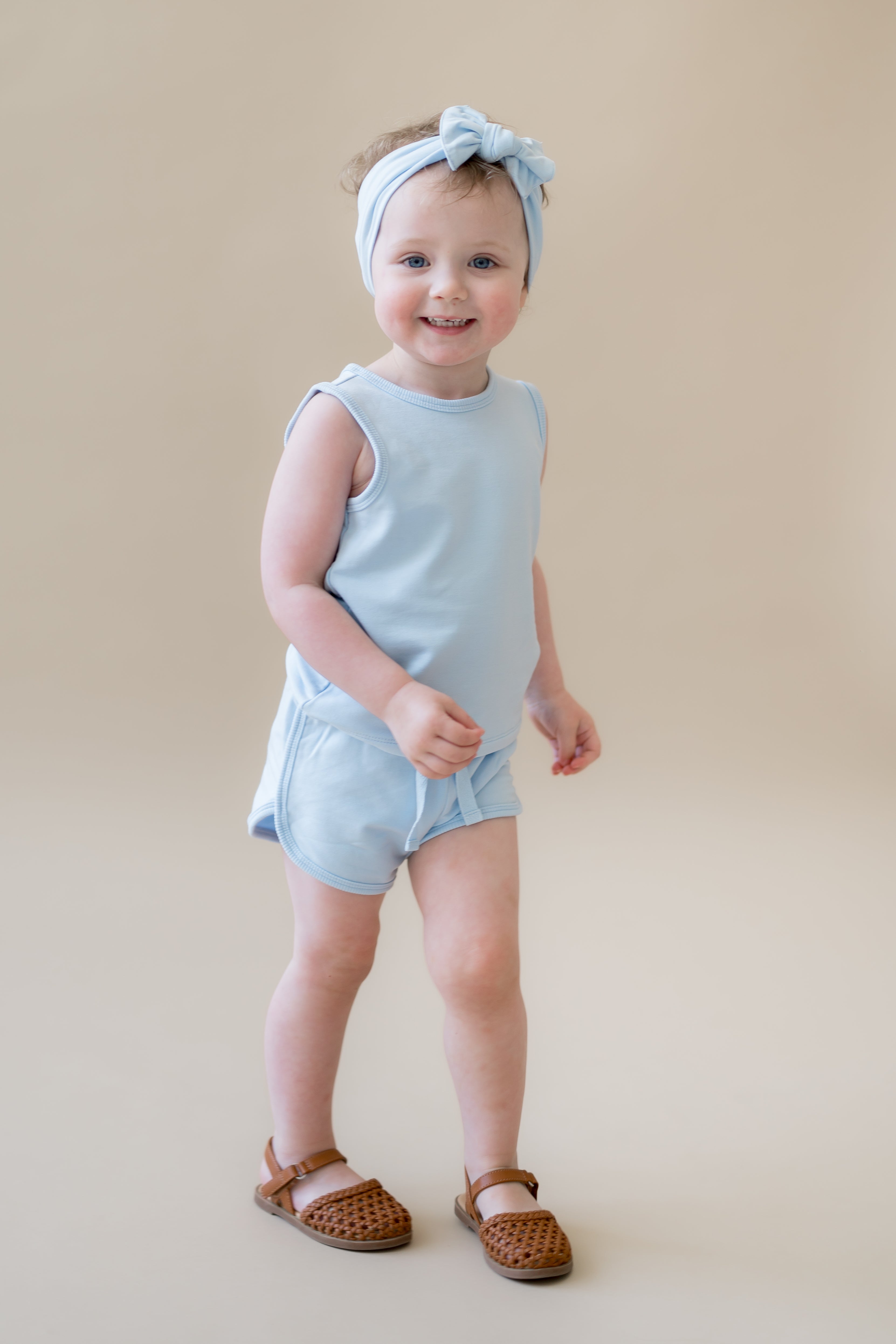 Young girl walking wearing the Tank Jogger Set in Breeze paired with a matching bow