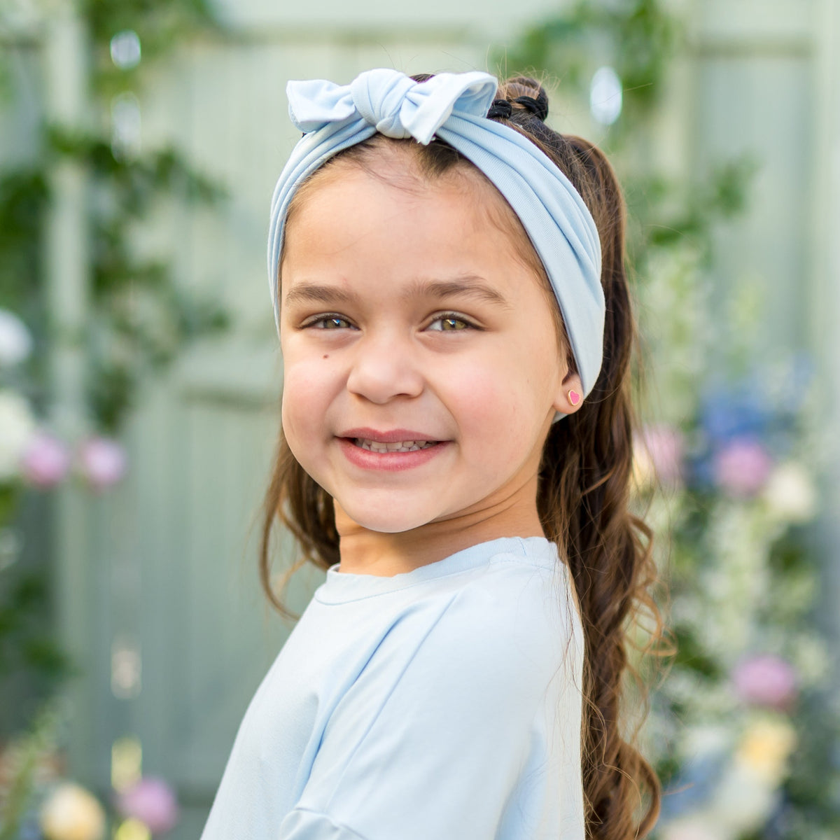 Young girl wearing the Knotted Bow Headband in Breeze