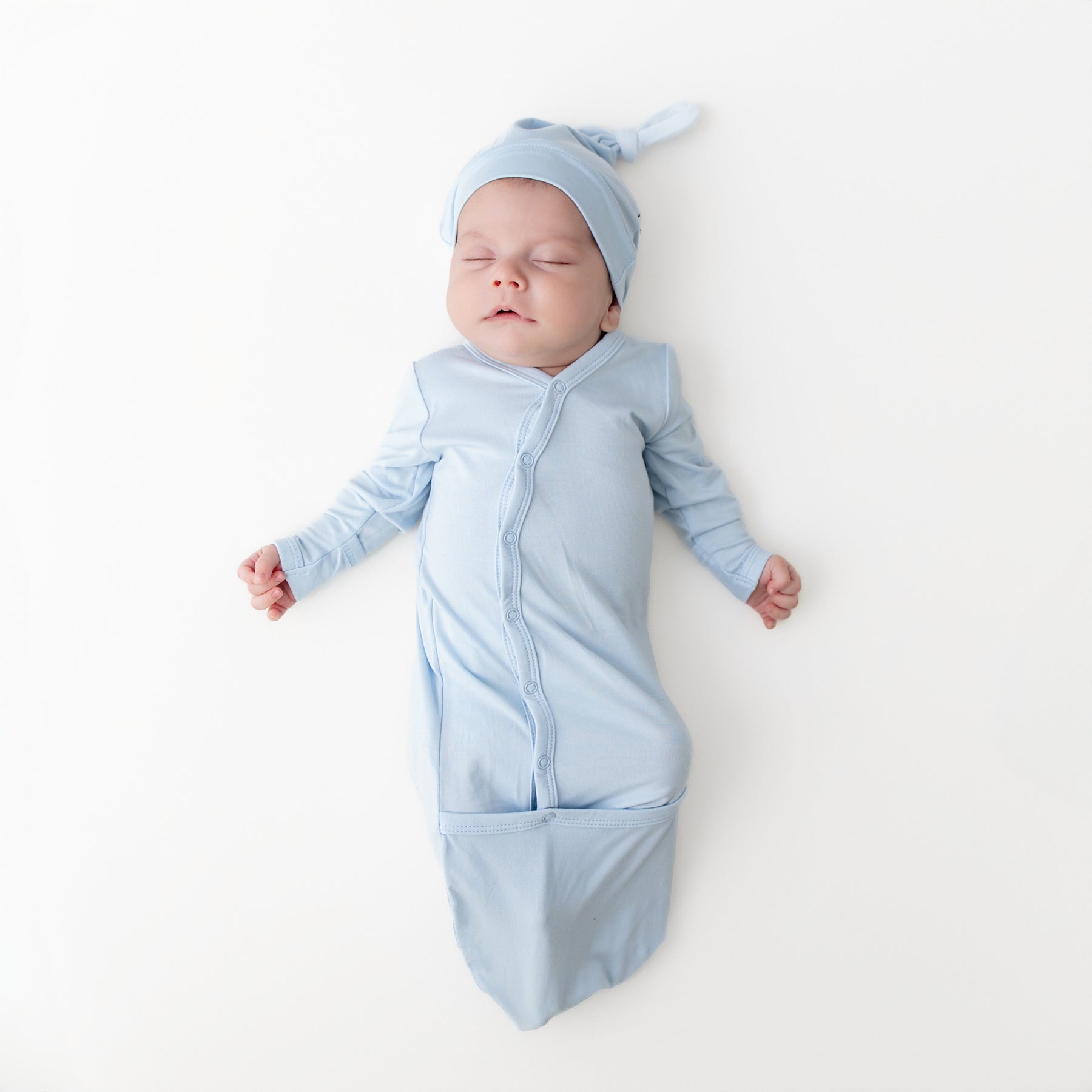 Sleeping newborn wearing the Bundler in Breeze with matching knotted cap