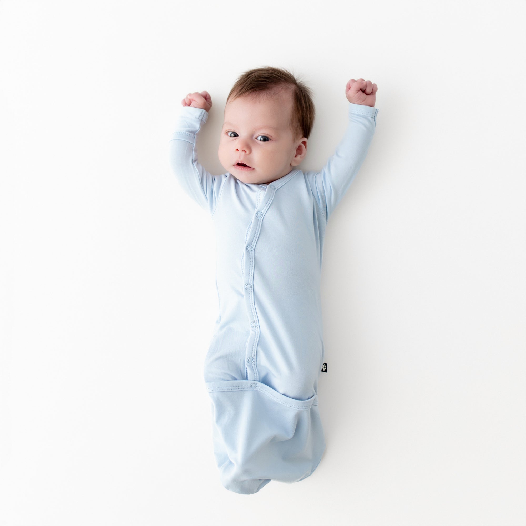 Newborn laying on a white surface wearing the Bundler in Breeze