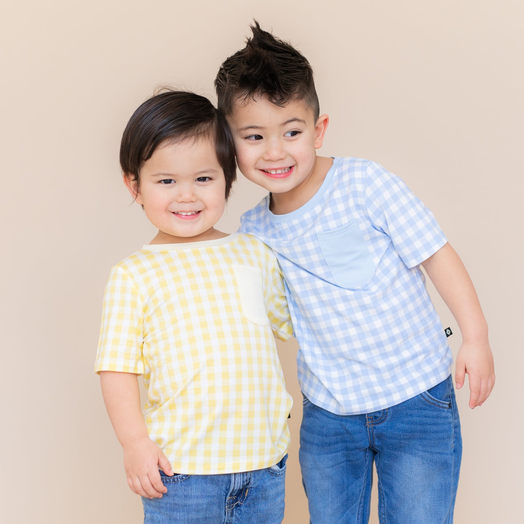 Two young boys standing side by side wearing the Toddler Crew Neck Tee in Gingham Chamomile and Gingham Breeze