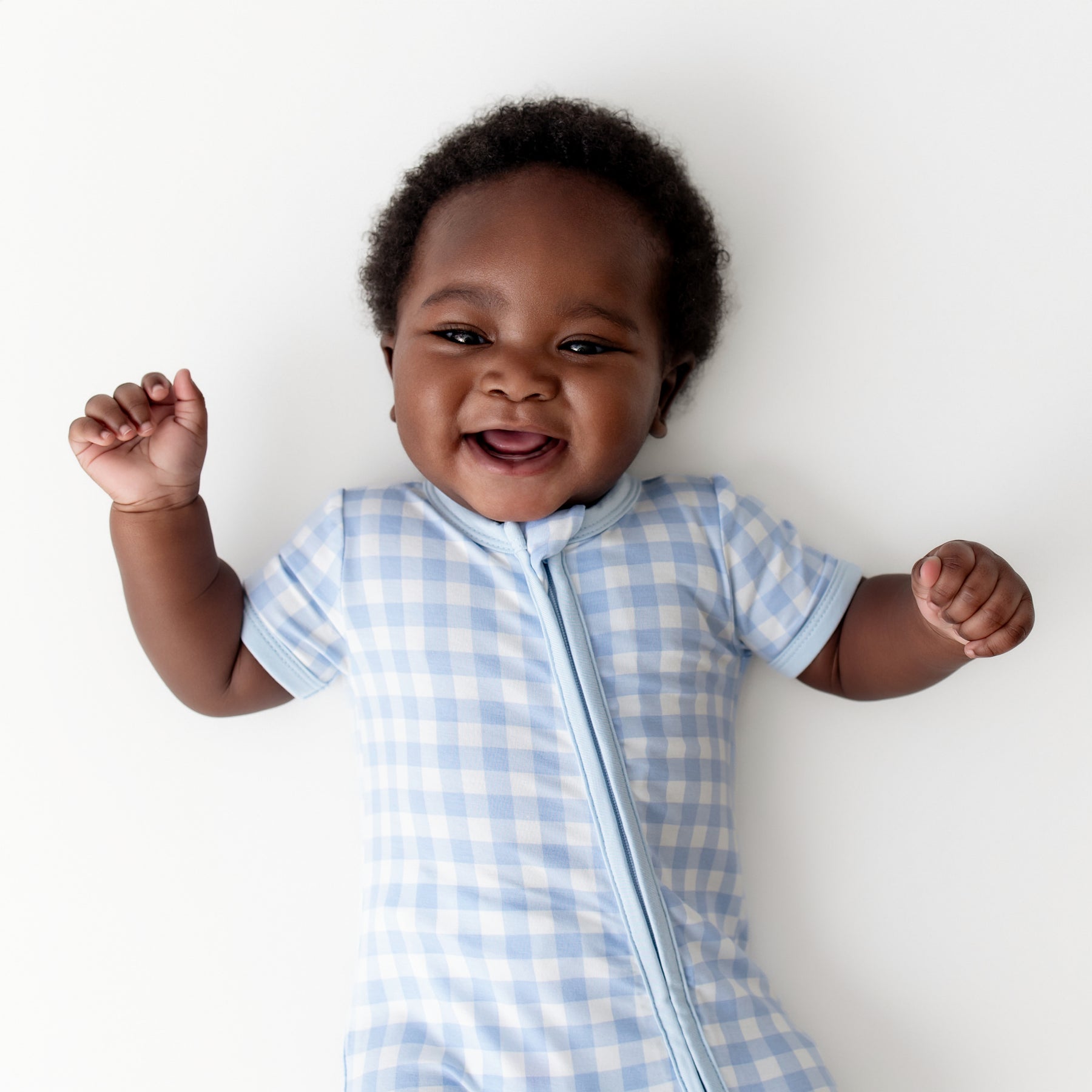 Close up of an infant wearing the Zipper Shortall Romper in Gingham Breeze