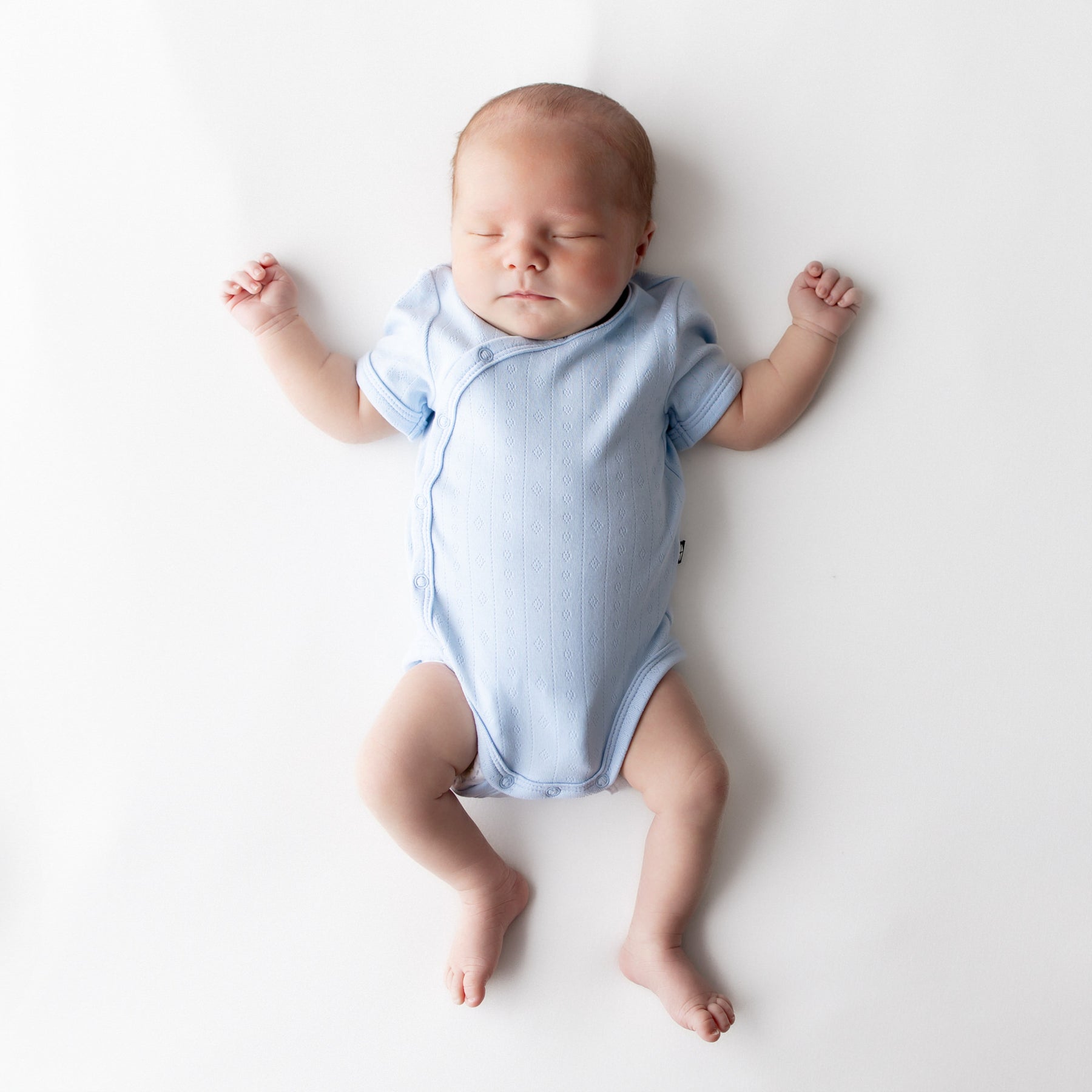 Sleeping newborn wearing the Pointelle Kimono Bodysuit in Breeze
