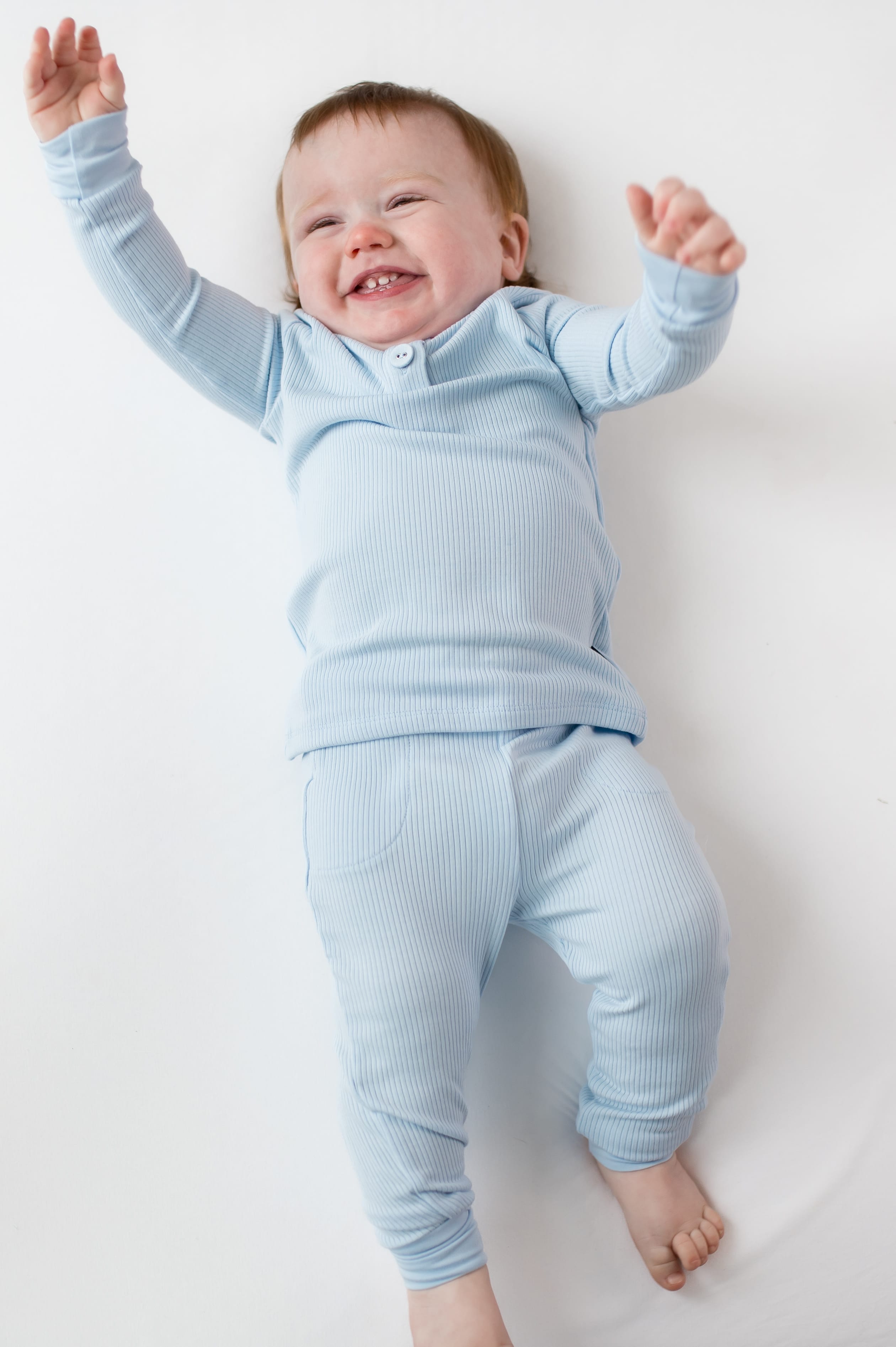 Young infant laying on a white surface wearing the Ribbed Infant Henley Set in Breeze