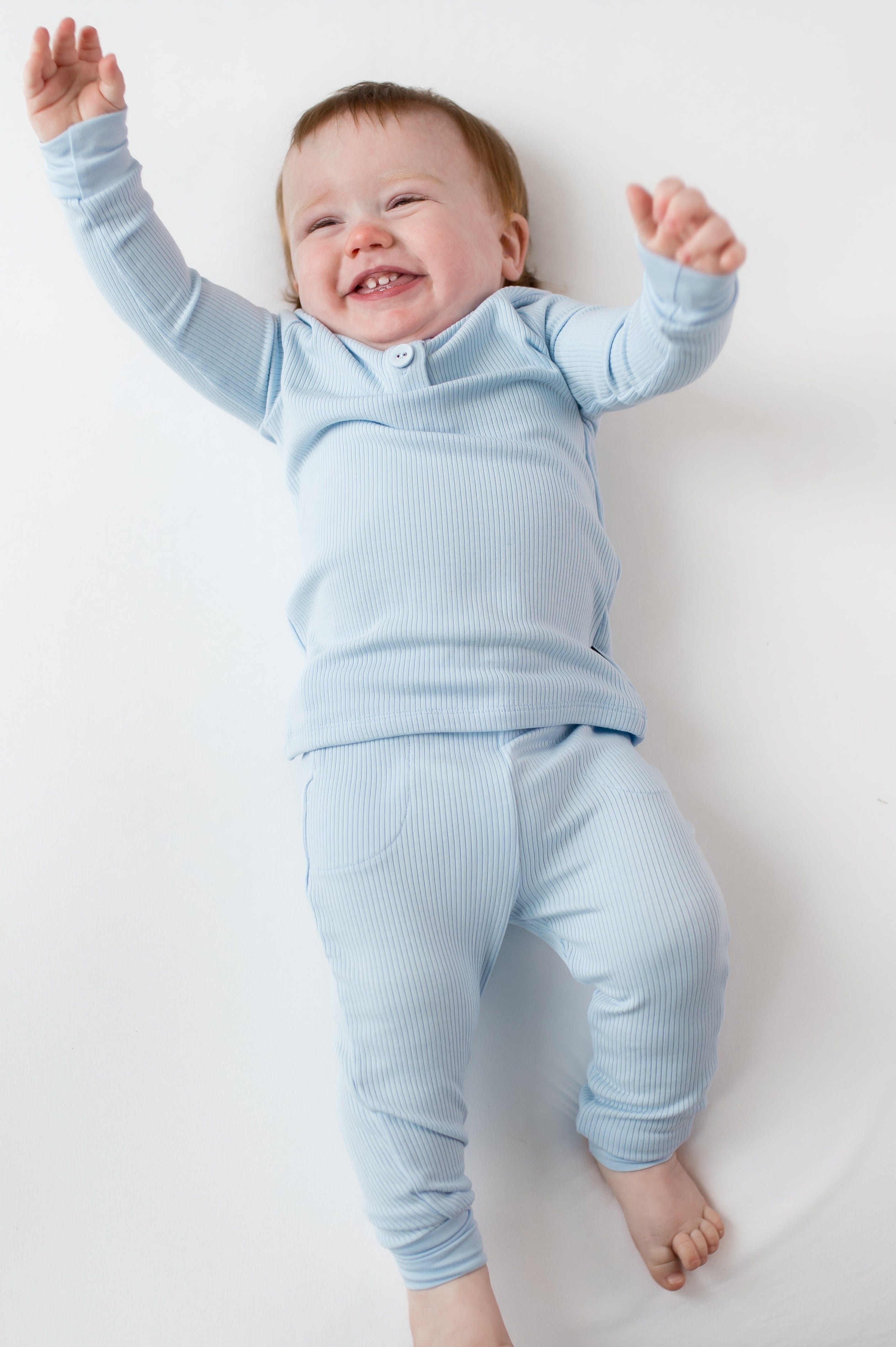 Young infant laying on a white surface wearing the Ribbed Infant Henley Set in Breeze