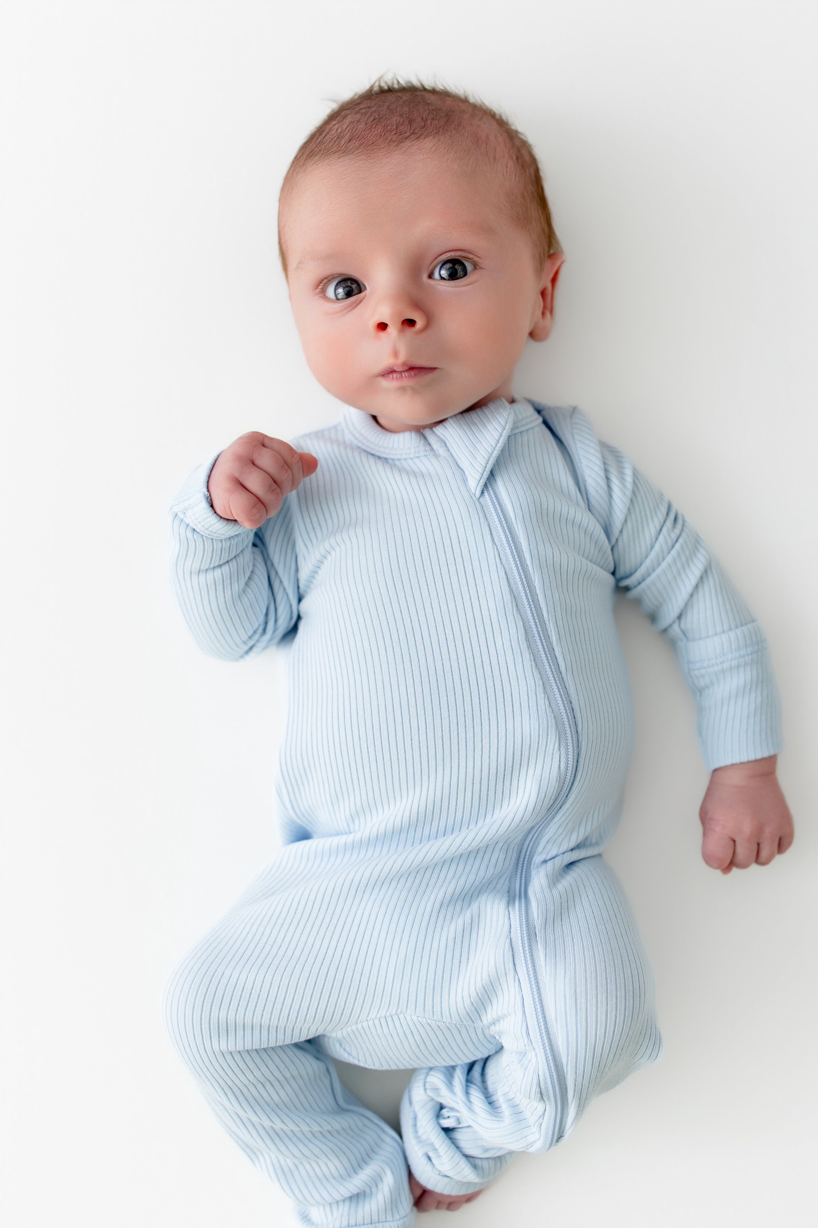Close up of newborn wearing the Ribbed Zipper Romper in Breeze