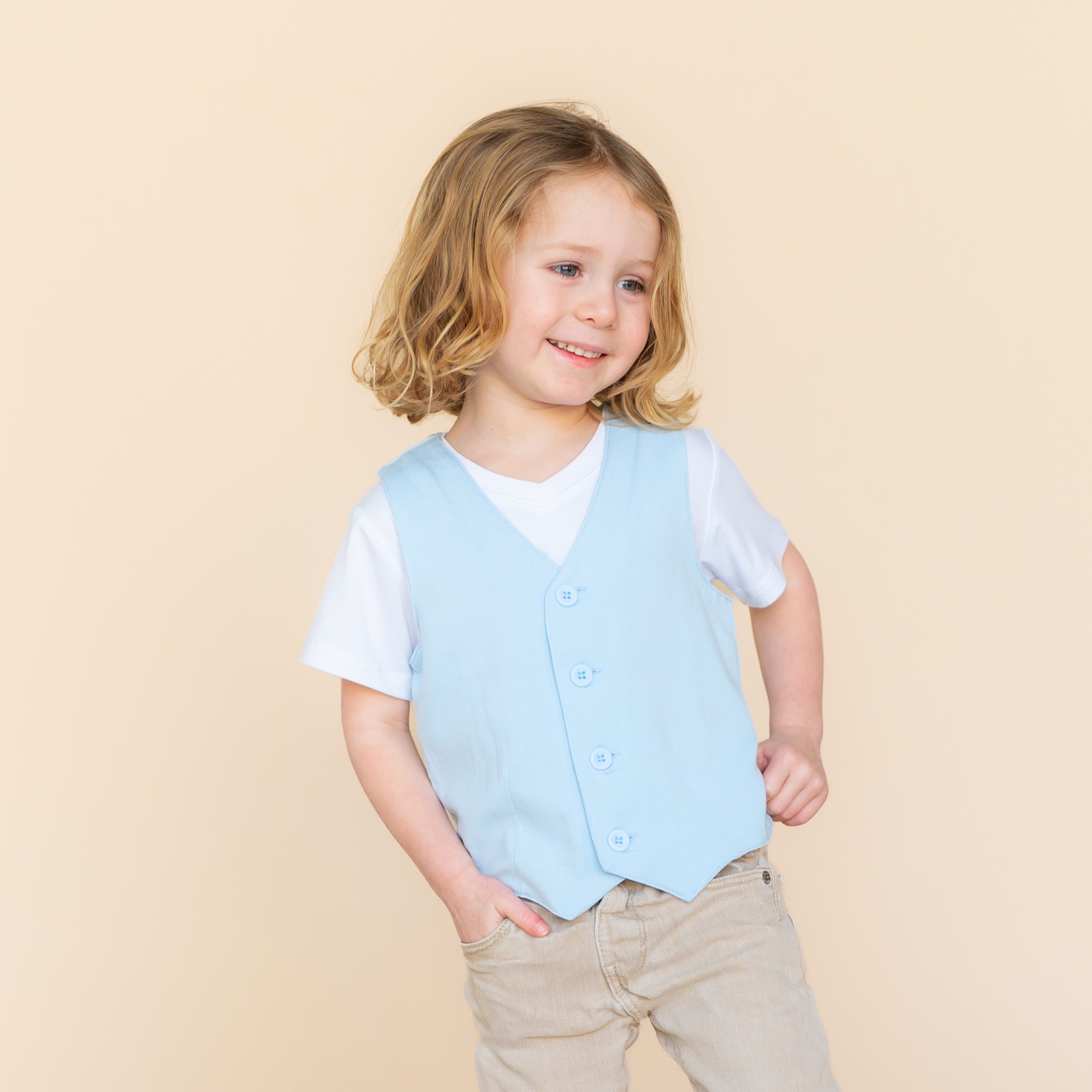 Smiling model wearing the Tuxedo Vest in Breeze with a white vneck shirt underneath