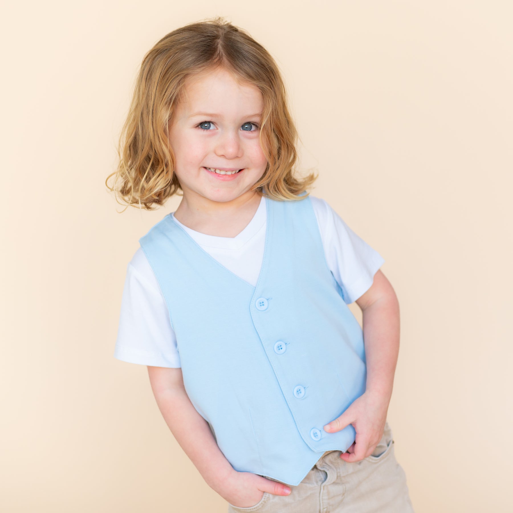 Close up of smiling model wearing the Tuxedo Vest in Breeze overtop a white vneck