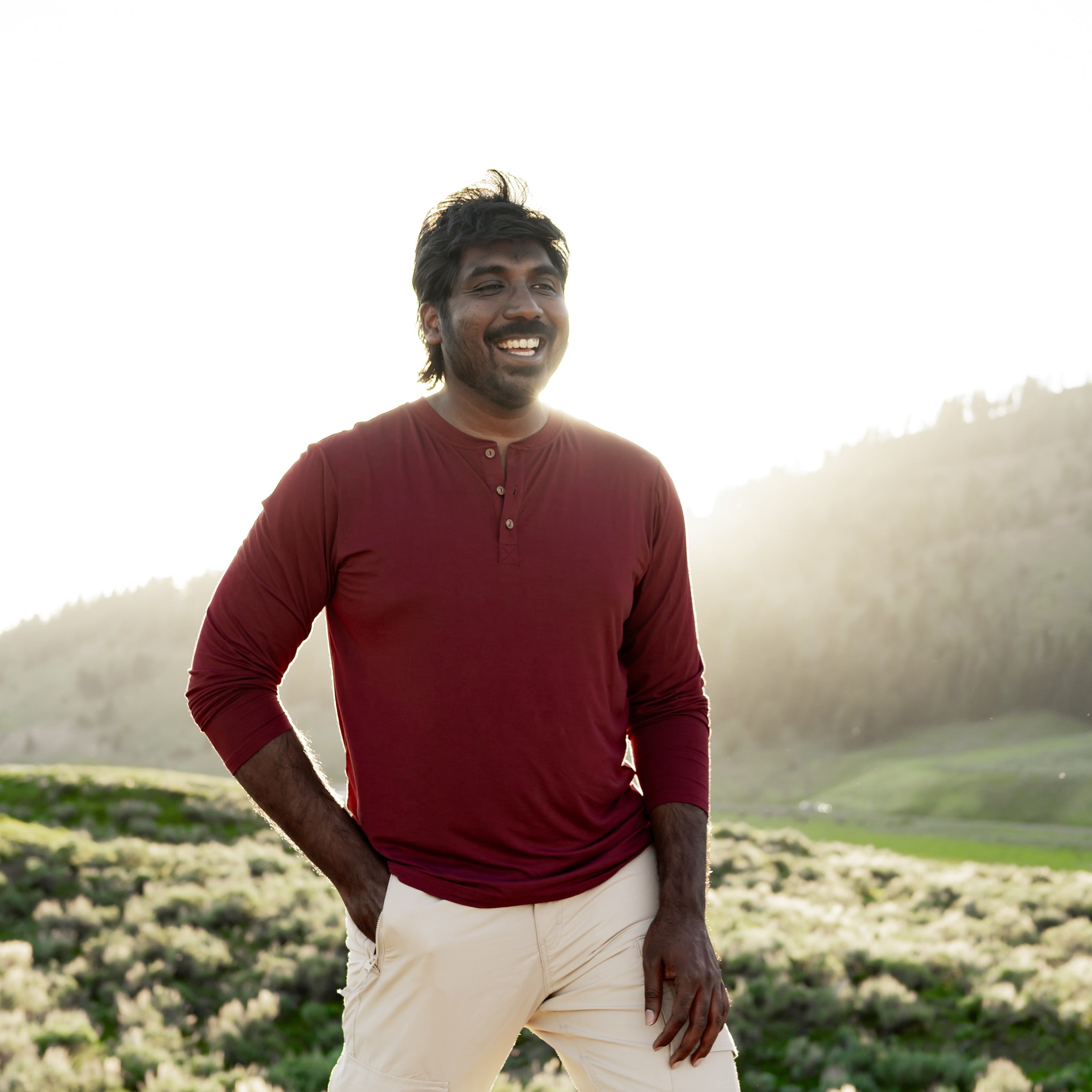 Smiling male model wearing the Men's Long Sleeve Henley Top in Burgundy